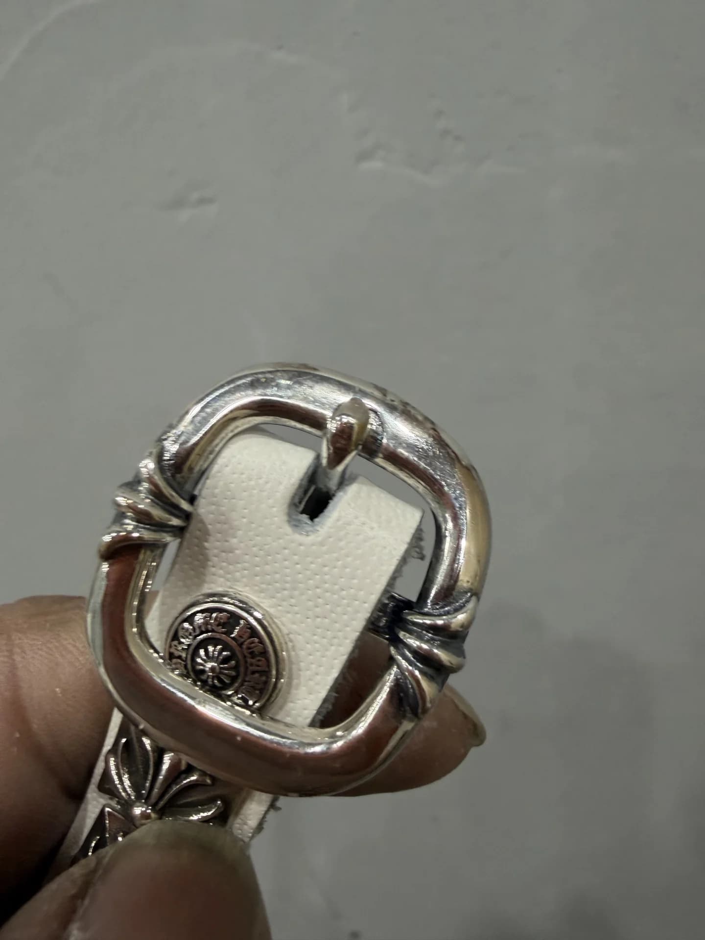 Крупный план серебряной пряжки белого ремня Chrome Hearts