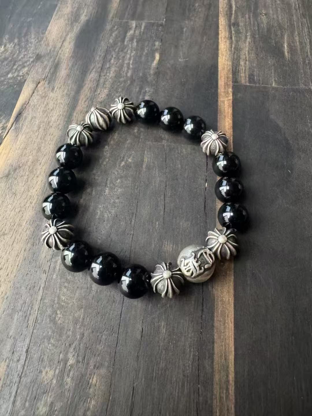 Браслет из обсидиановых бусин и серебра Chrome Hearts на деревянной поверхности