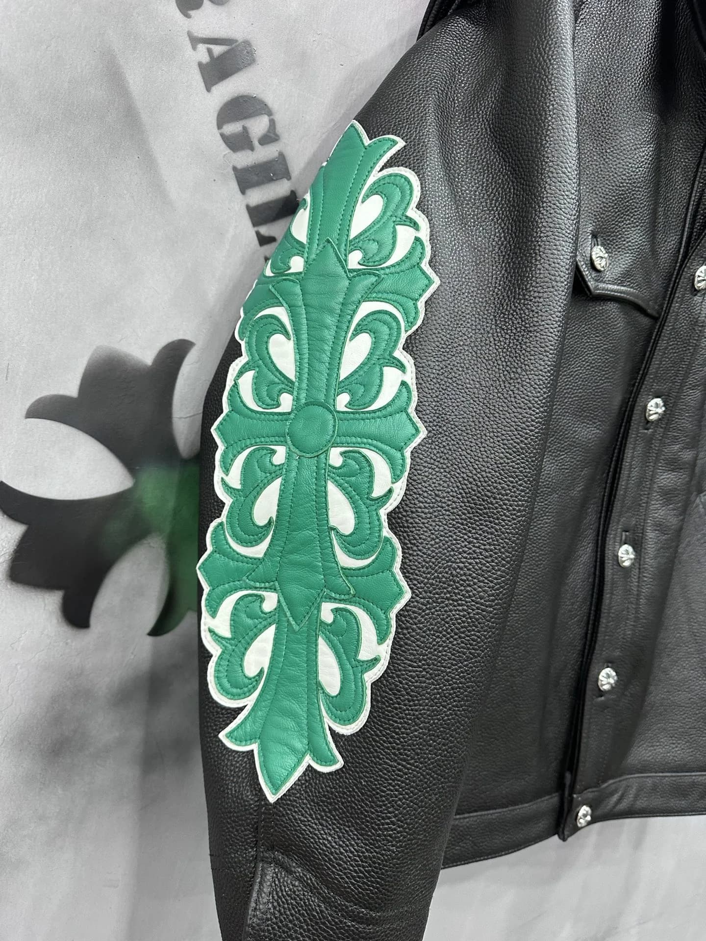 Зеленая нашивка в виде креста на рукаве кожаной куртки Chrome Hearts