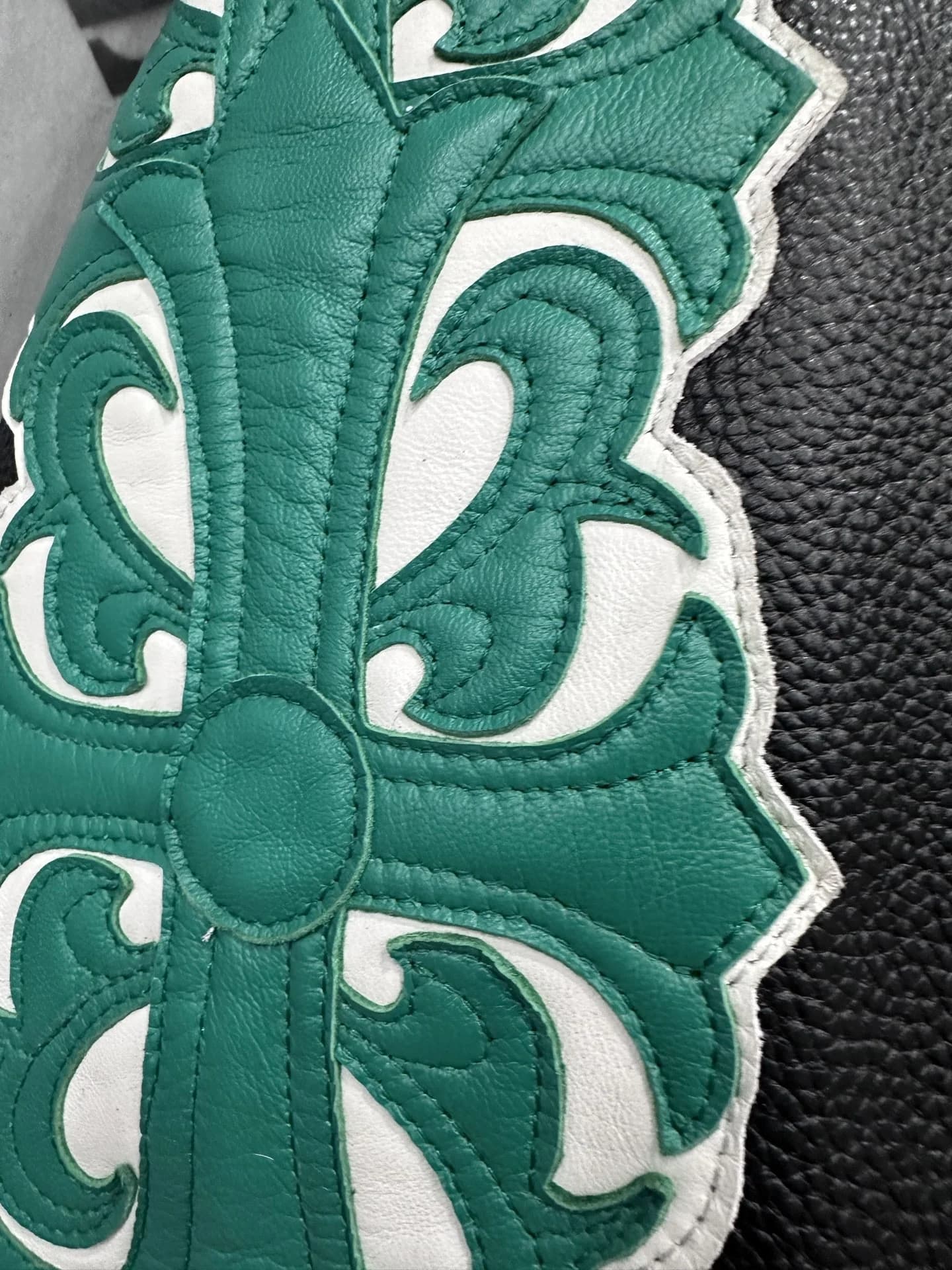 Крупный план кожаной нашивки зеленого цвета на рукаве куртки Chrome Hearts