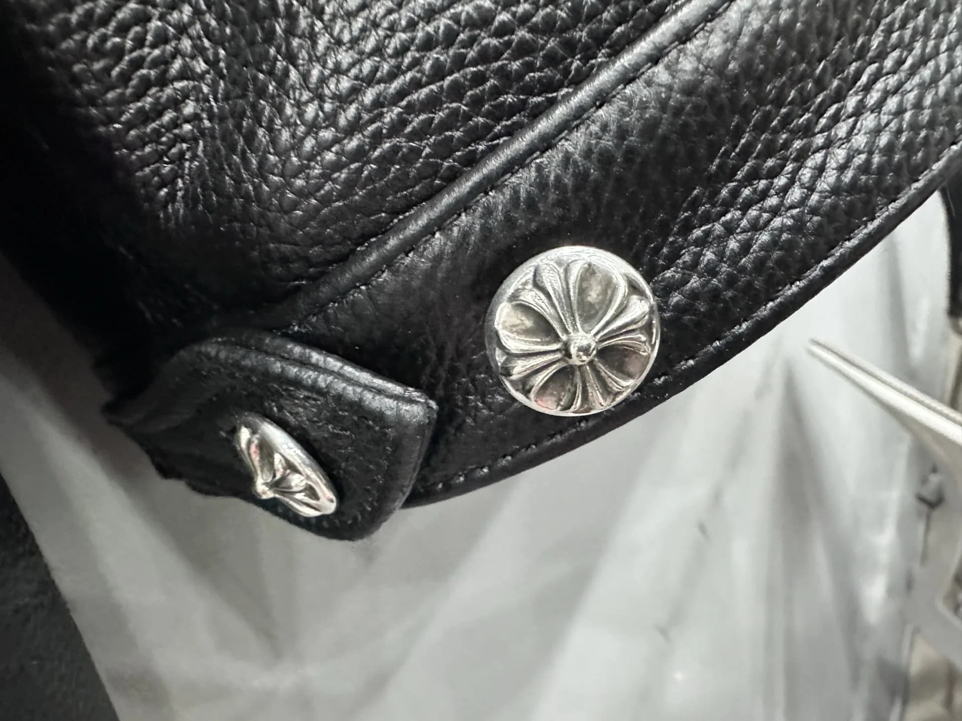 Металлическая кнопка с фирменным крестом на манжете куртки Chrome Hearts