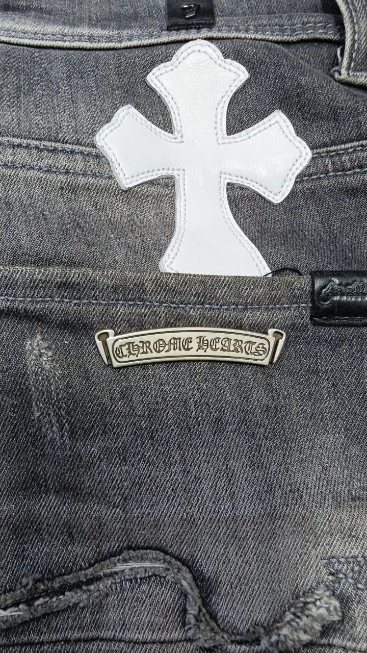 Деталь заднего кармана джинсов Chrome Hearts с кожаным крестом и серебряной пластиной с логотипом