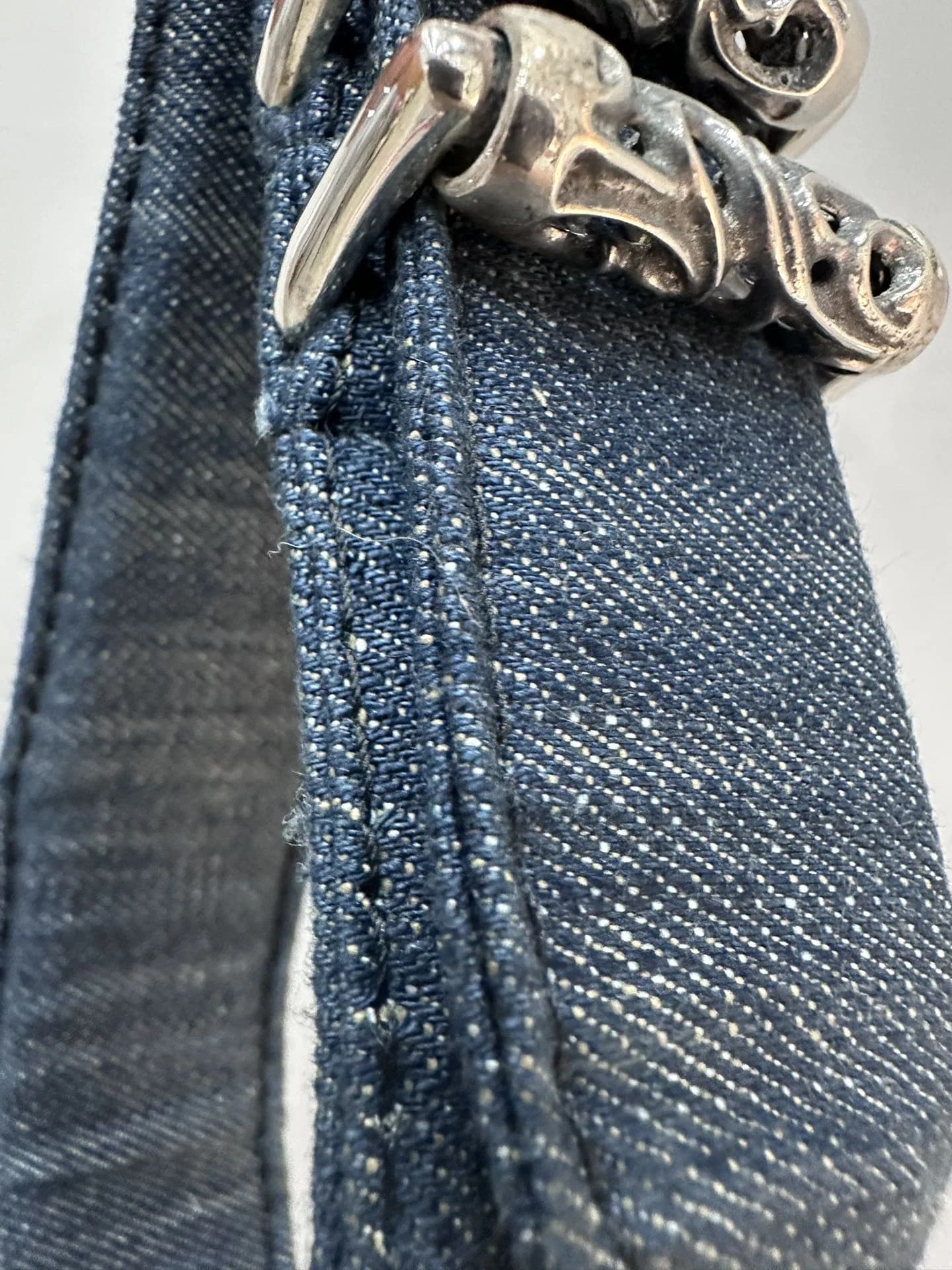Деталь джинсовой ткани и серебряного декора ремня Chrome Hearts