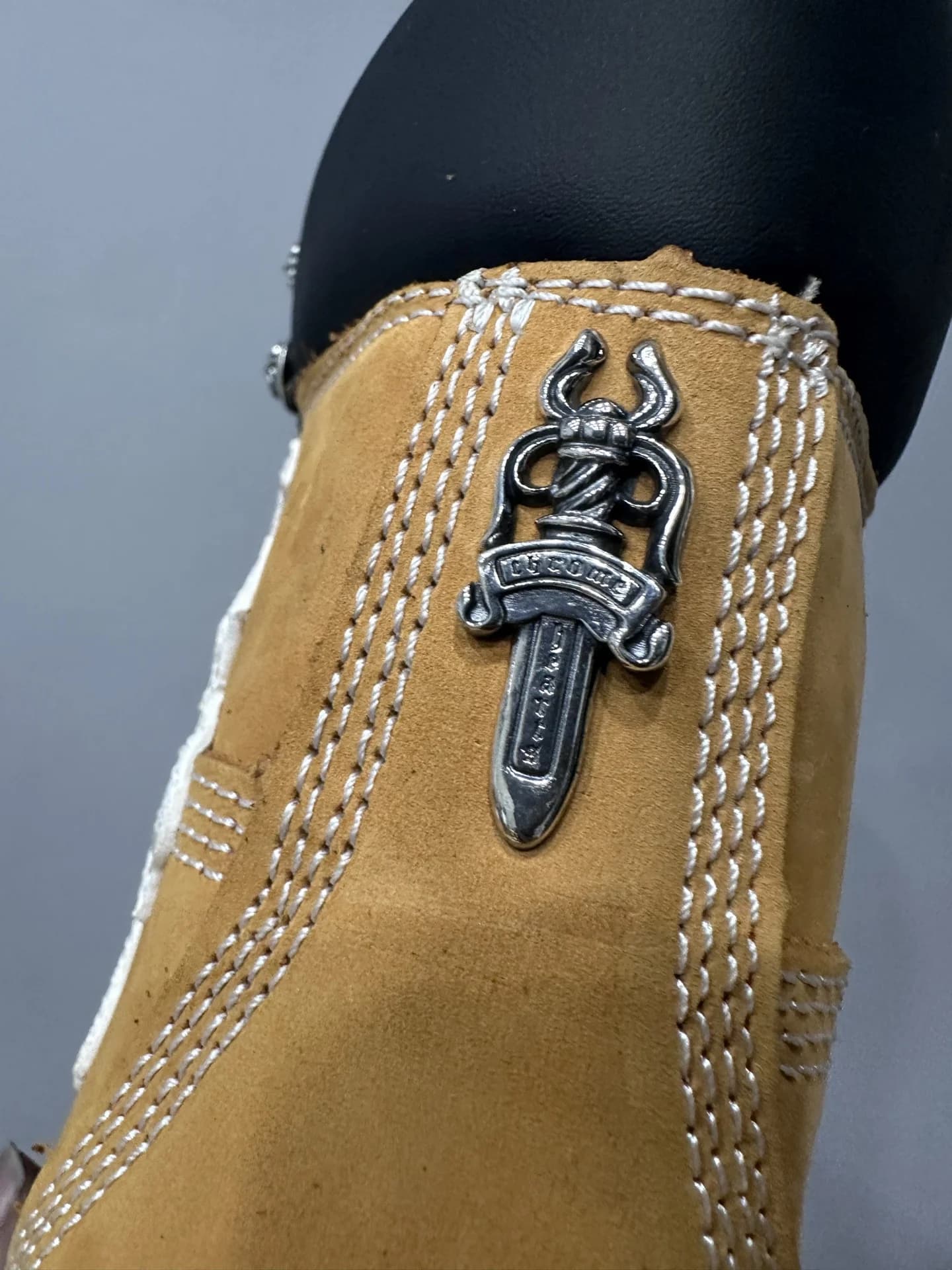Серебряная декоративная деталь в виде кинжала на заднике ботинка Chrome Hearts