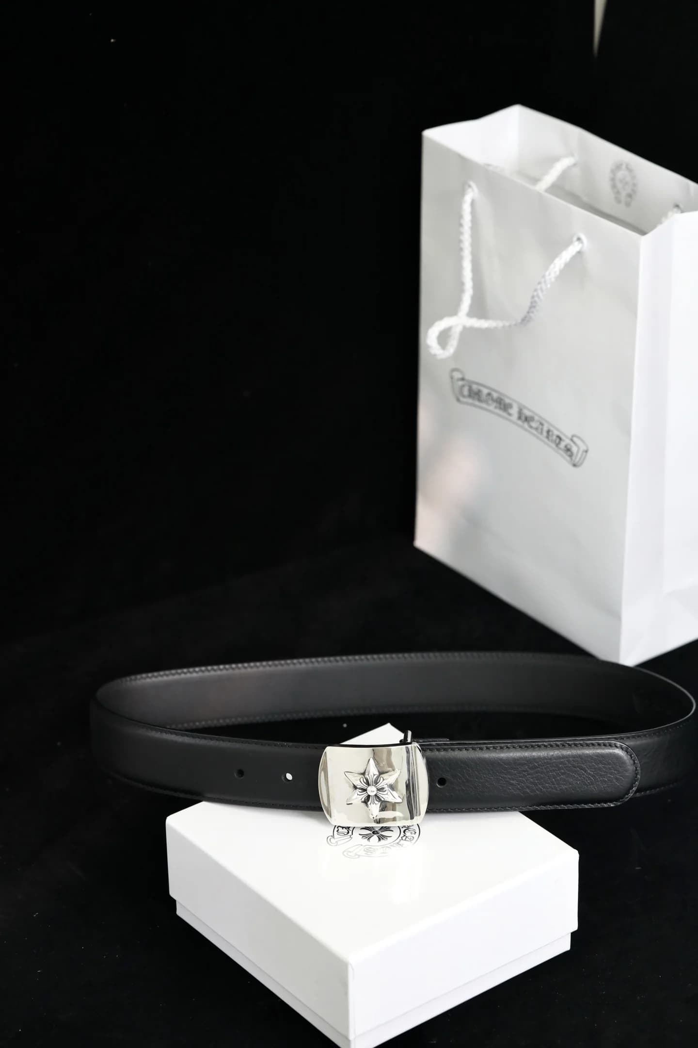 Чёрный кожаный ремень Chrome Hearts с серебряной пряжкой на фоне фирменной упаковки