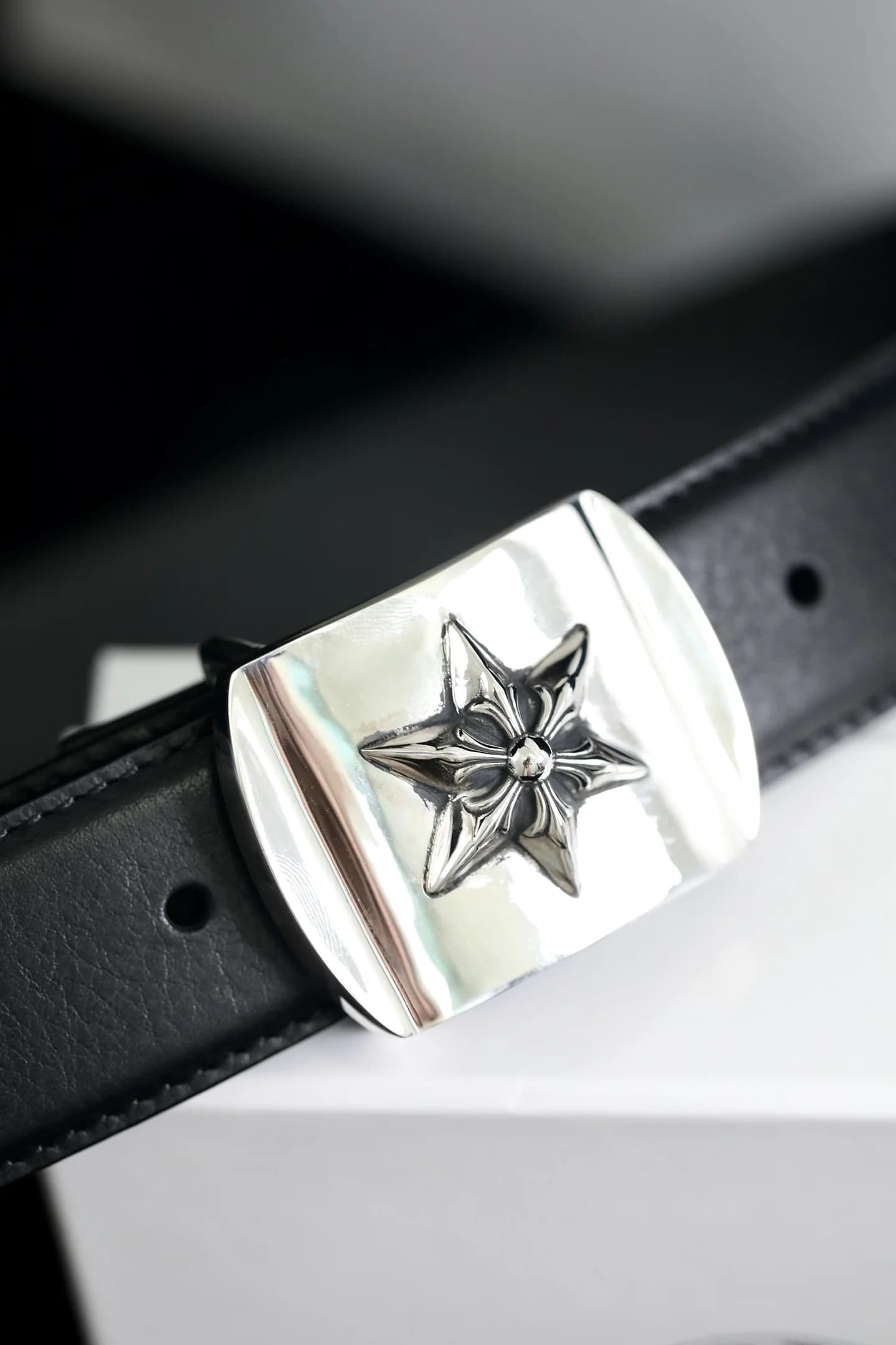 Крупный план серебряной пряжки Chrome Hearts с мотивом звезды