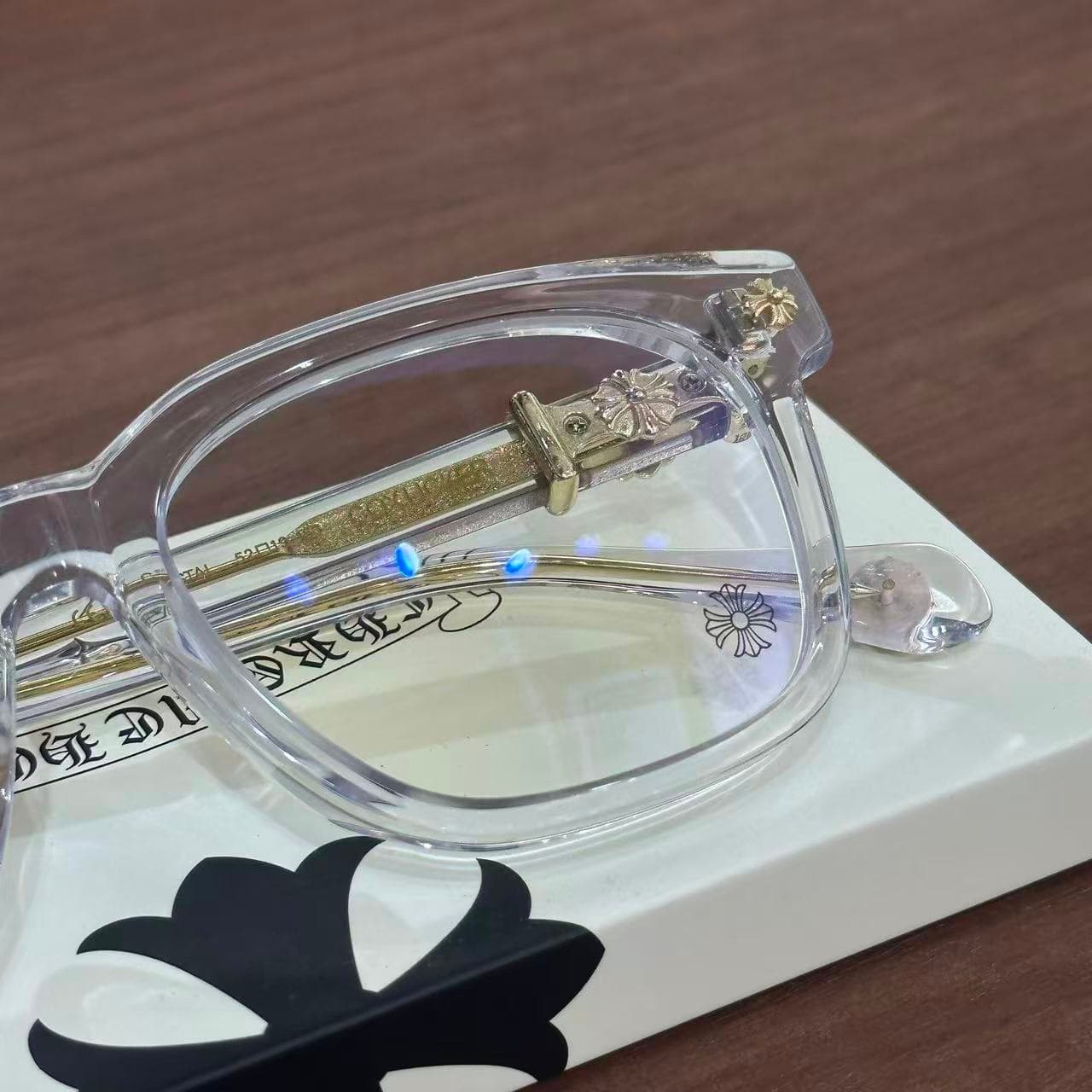 Крупный план прозрачной оправы и шарнира очков Chrome Hearts COX UCKER