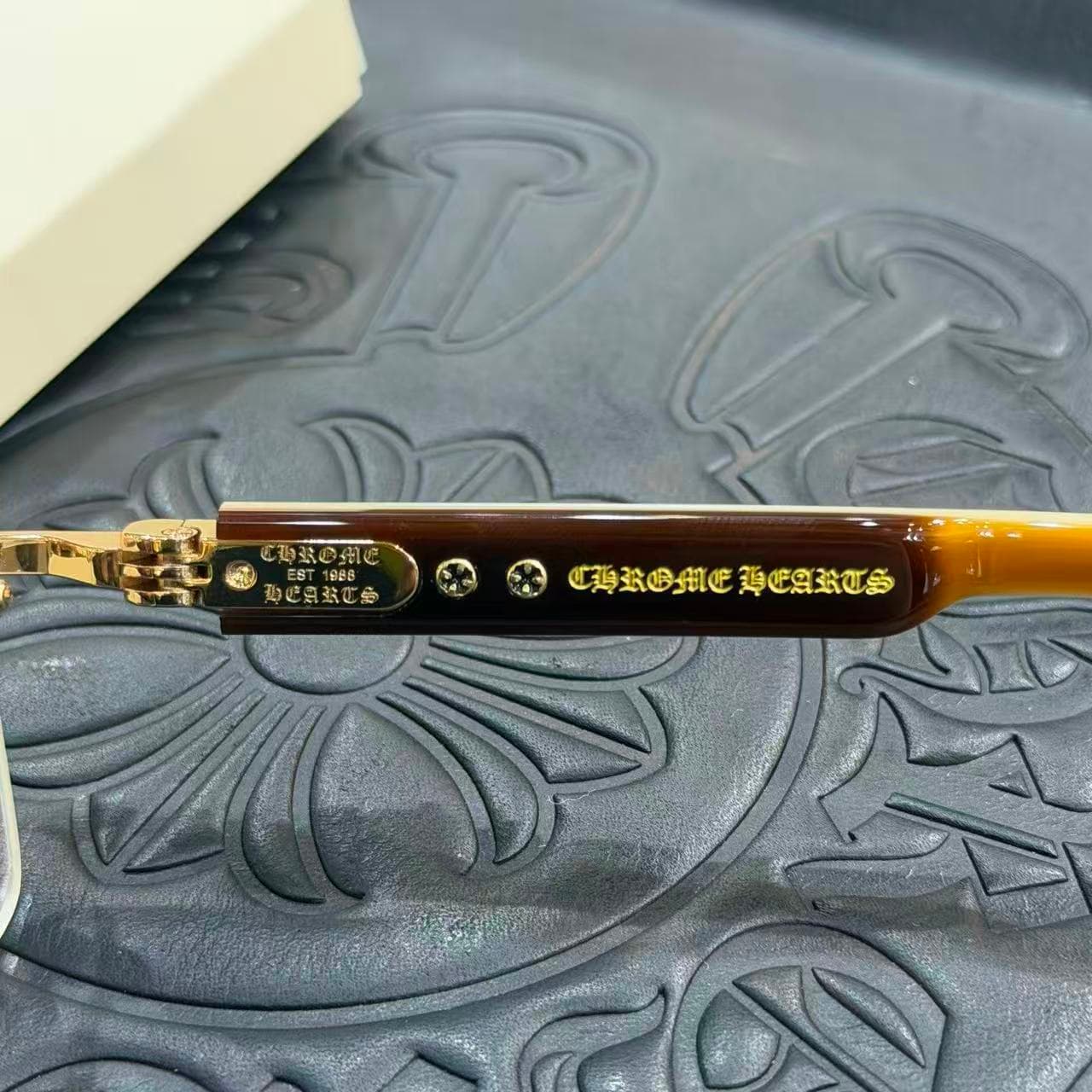 Крупный план дужки с гравировкой Chrome Hearts и золотистым декором