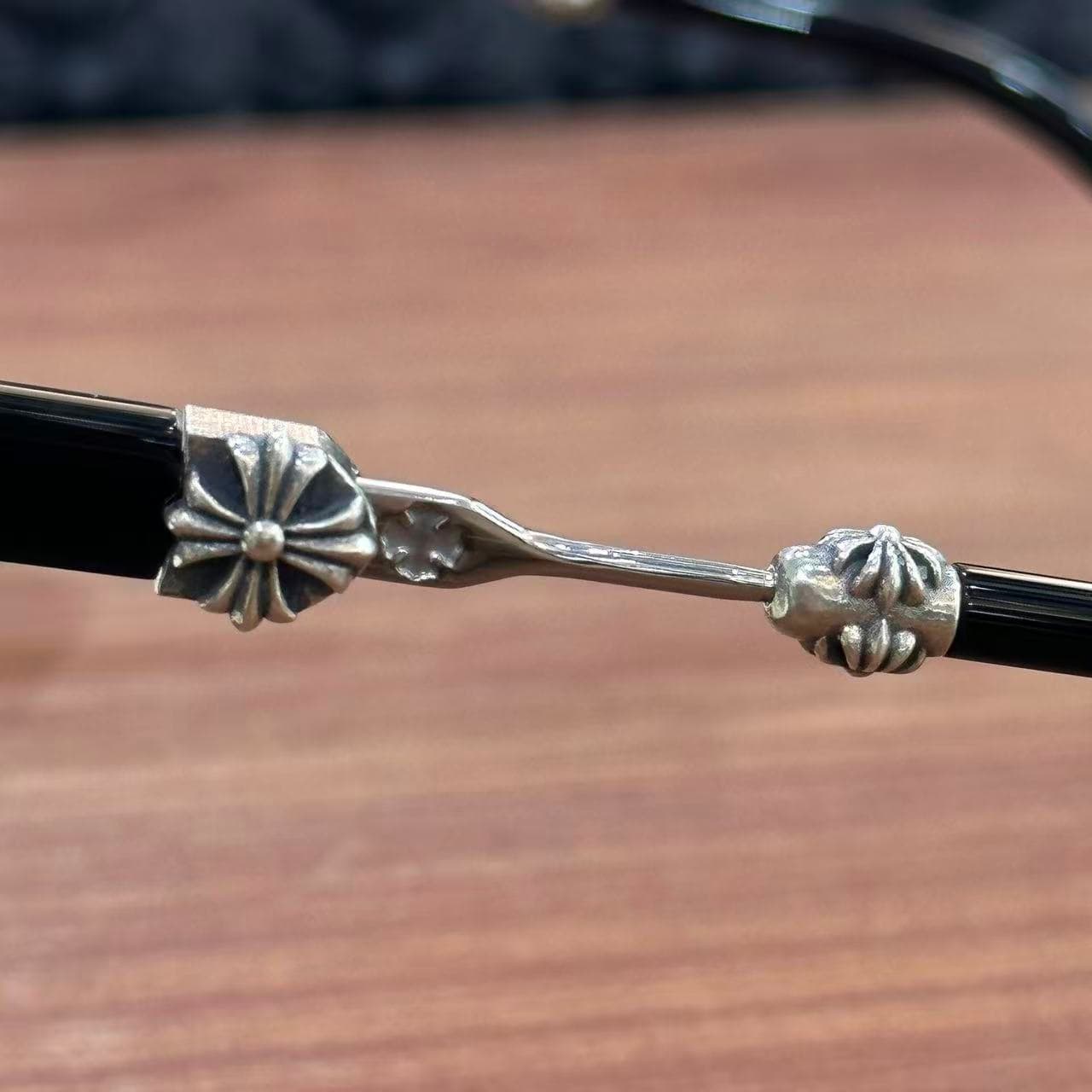 Крупный план серебряной вставки с крестом на дужке очков Chrome Hearts