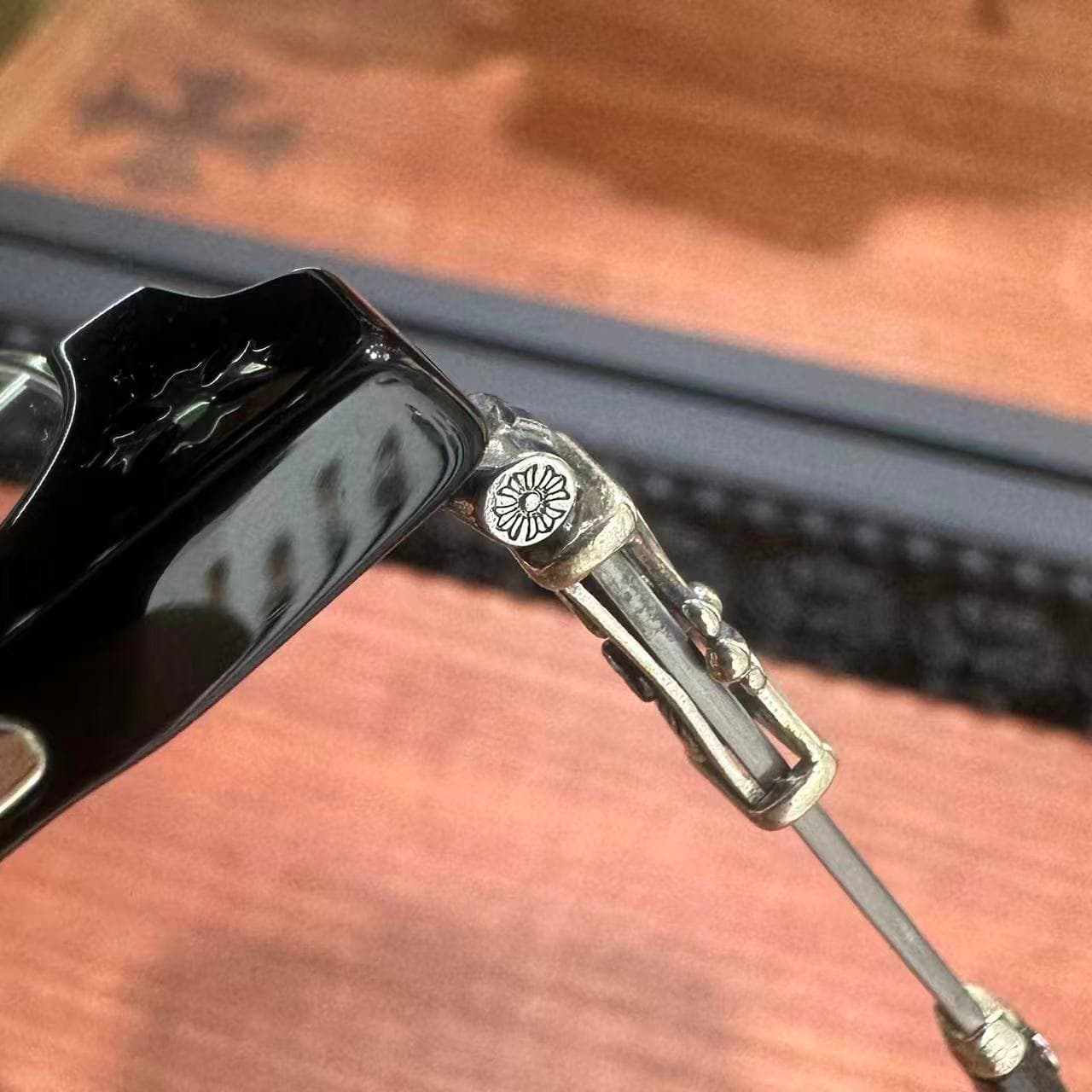 Крупный план шарнирного соединения и серебряного декора очков Chrome Hearts