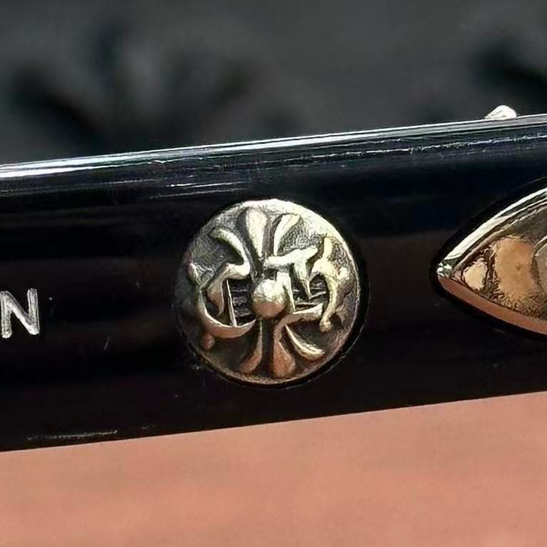 Крупный план серебряного креста Chrome Hearts на черной дужке