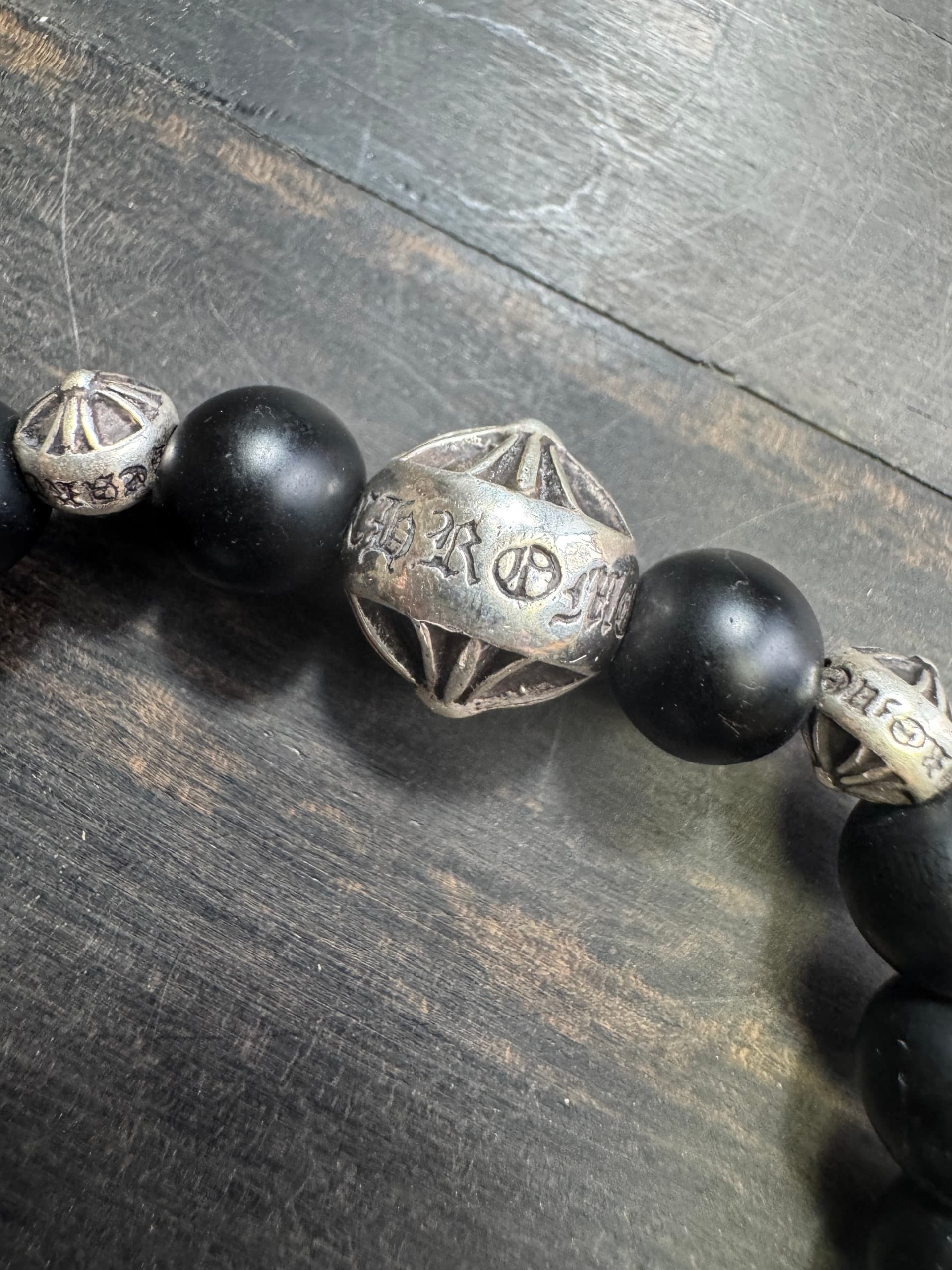 Центральная серебряная бусина с гравировкой Chrome Hearts крупным планом