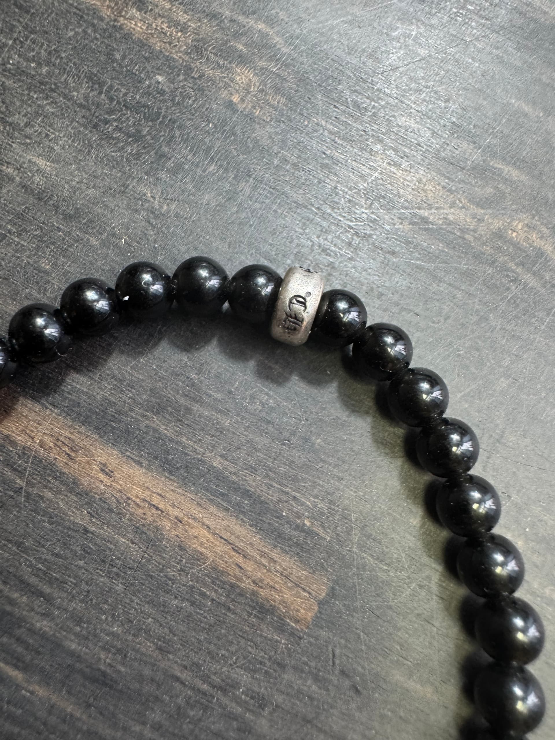 Серебряная бусина-разделитель с гравировкой на браслете из камня Chrome Hearts крупным планом