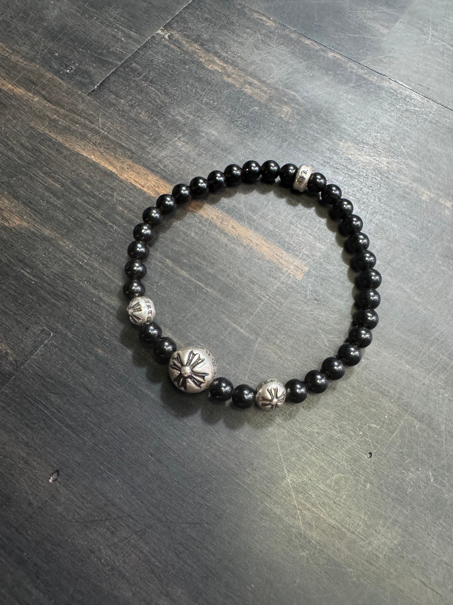 Браслет из бусин черного камня и серебра 925 пробы Chrome Hearts на темном деревянном фоне