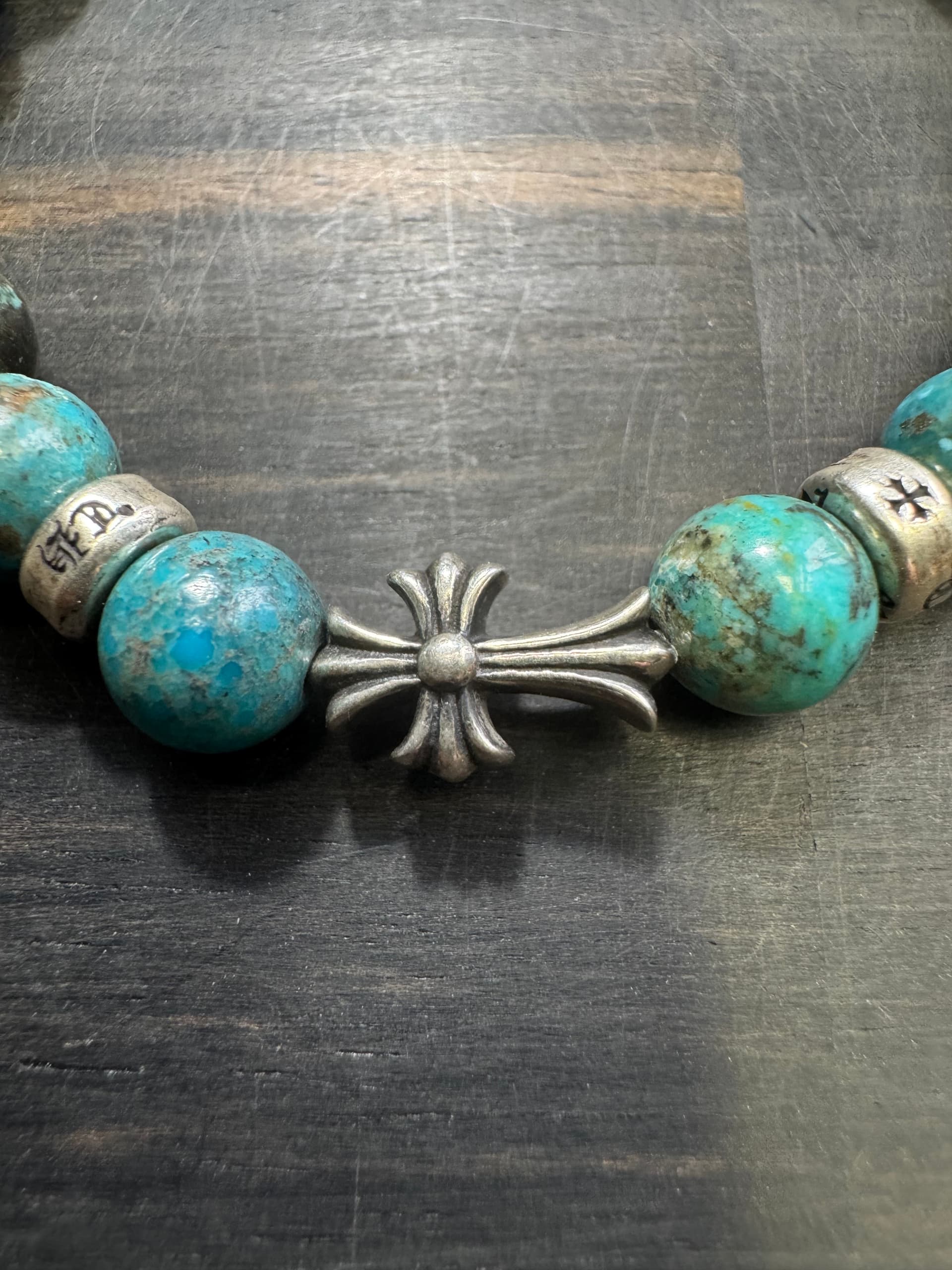 Крупный план центрального серебряного креста на браслете Chrome Hearts