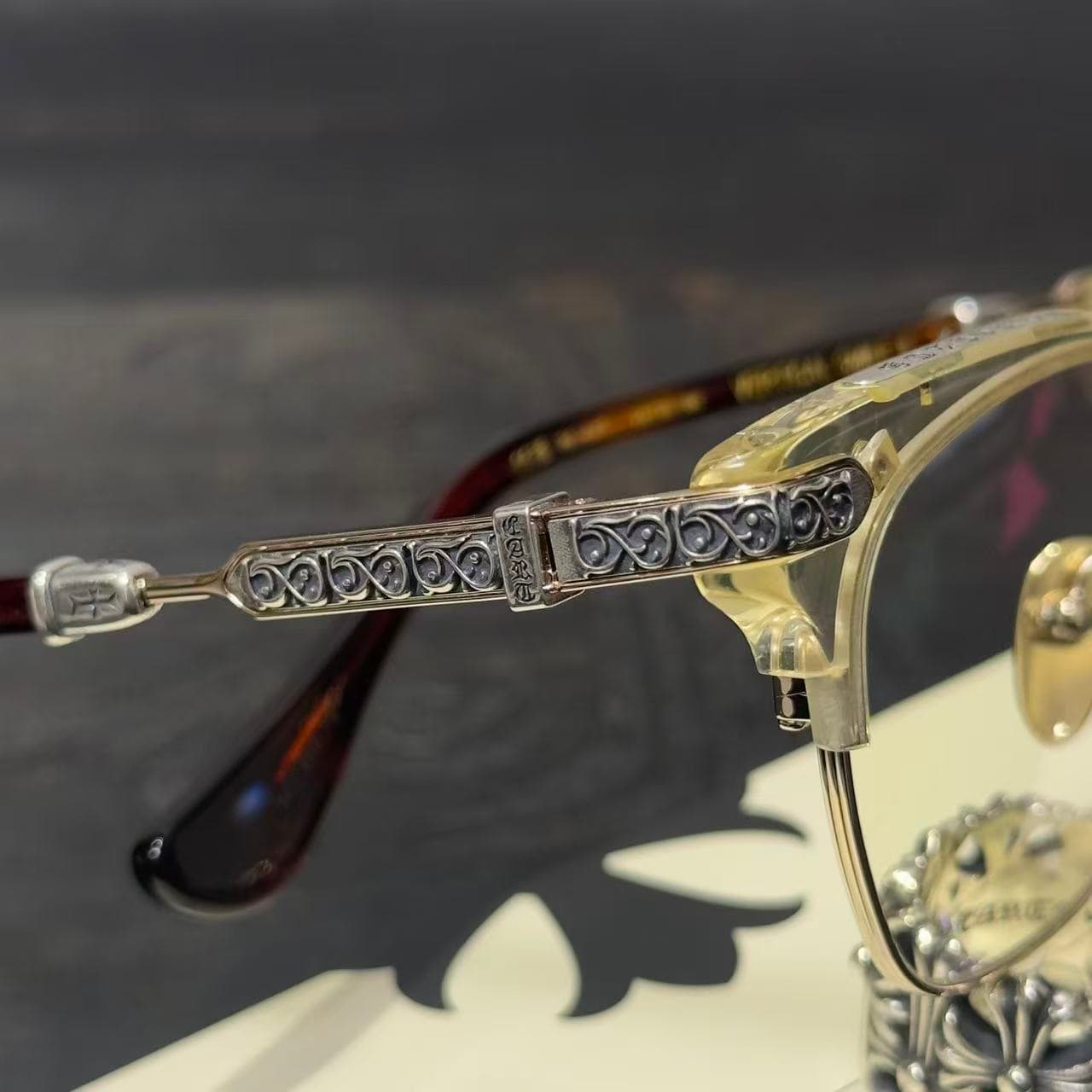 Крупный план резного серебряного декора на заушнике очков Chrome Hearts VERTICAL SMILE II