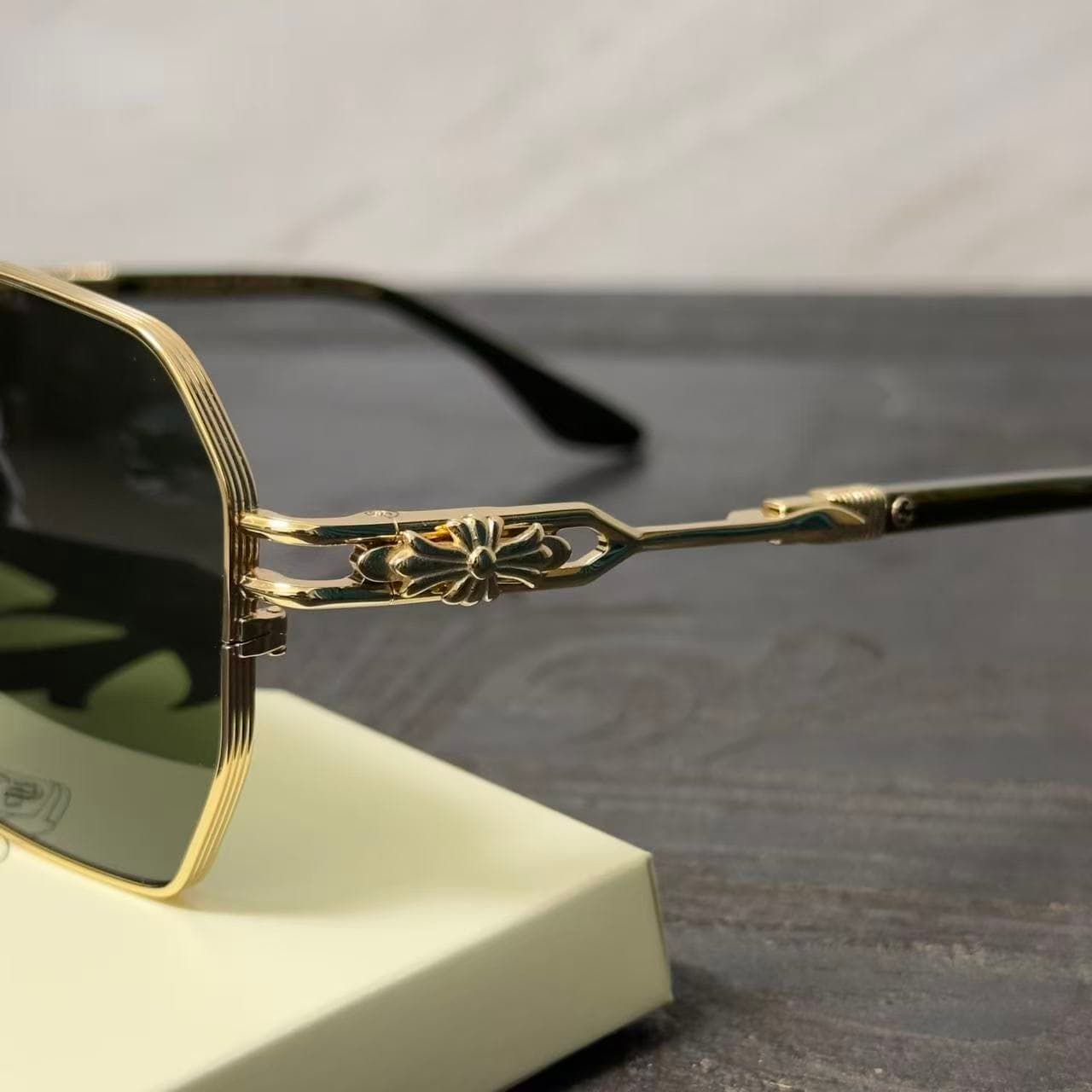Крупный план шарнирного соединения и фирменного креста на дужке очков Chrome Hearts RIPPING