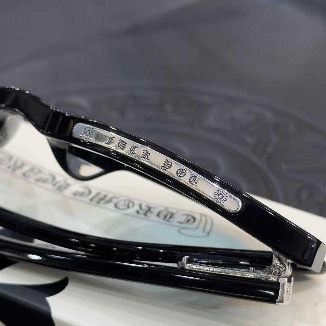 Деталь серебряной накладки с готической гравировкой CHROME HEARTS на верхней части оправы