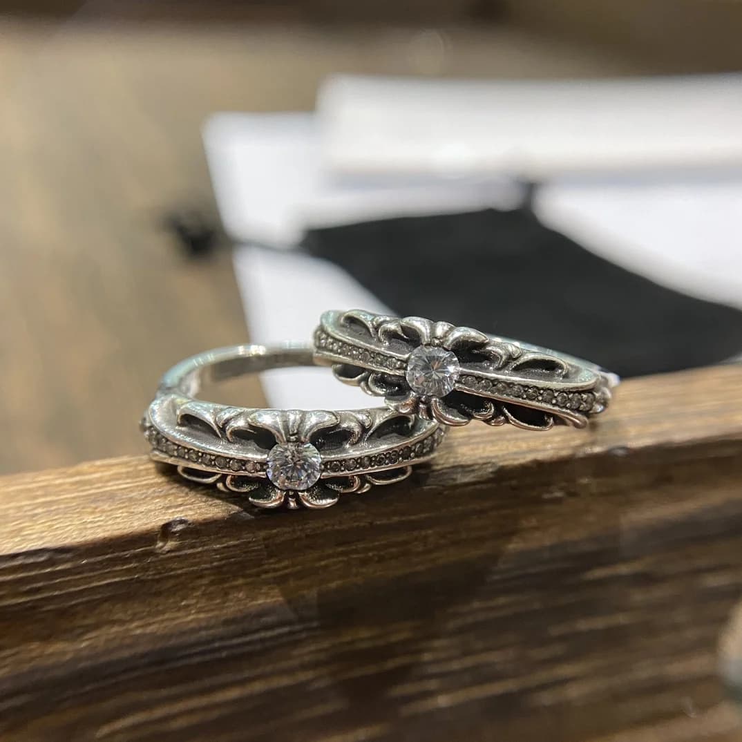 Два серебряных кольца Chrome Hearts Baby Floral с камнями на деревянной поверхности