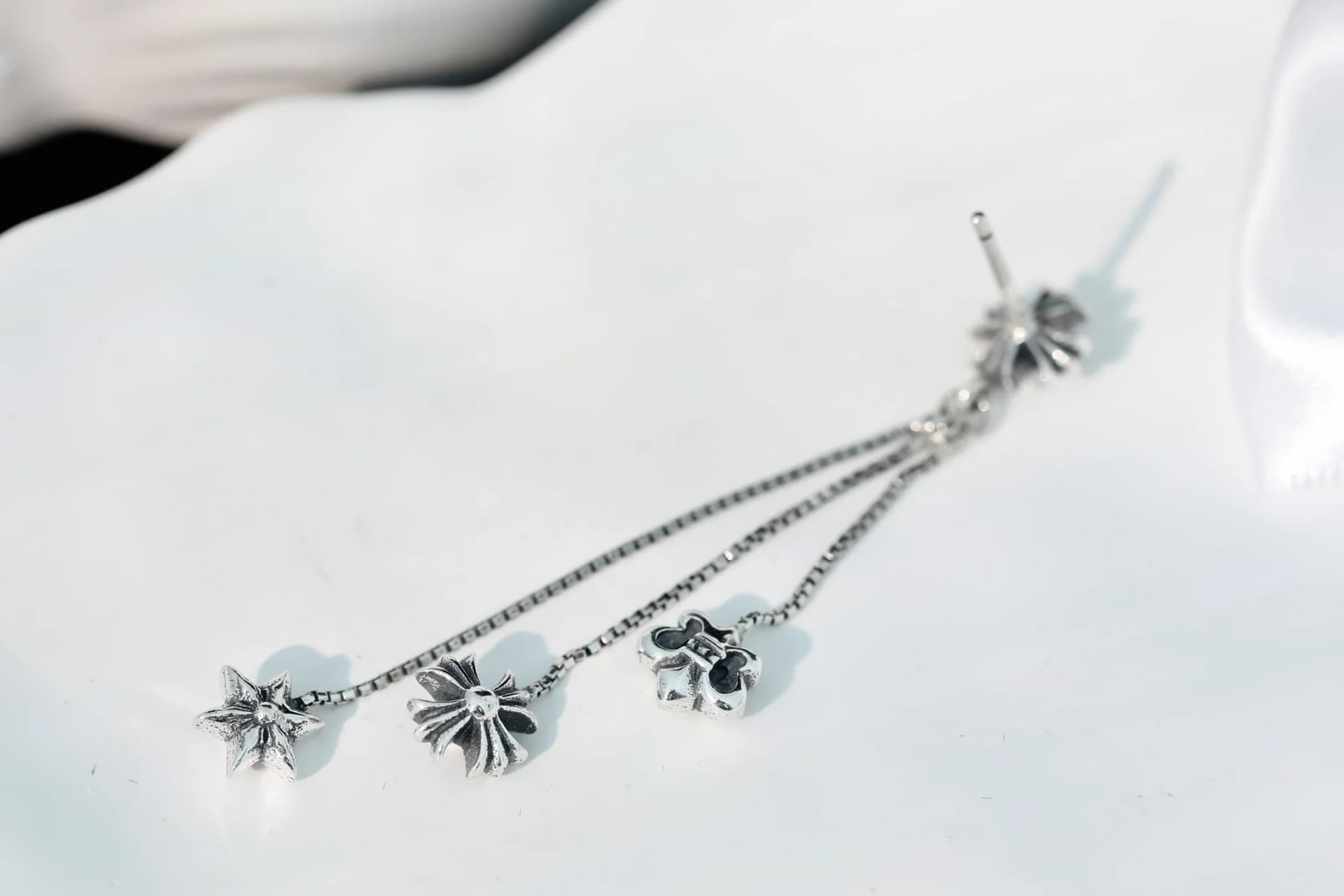 Серебряная серьга Chrome Hearts с подвесками на белой поверхности