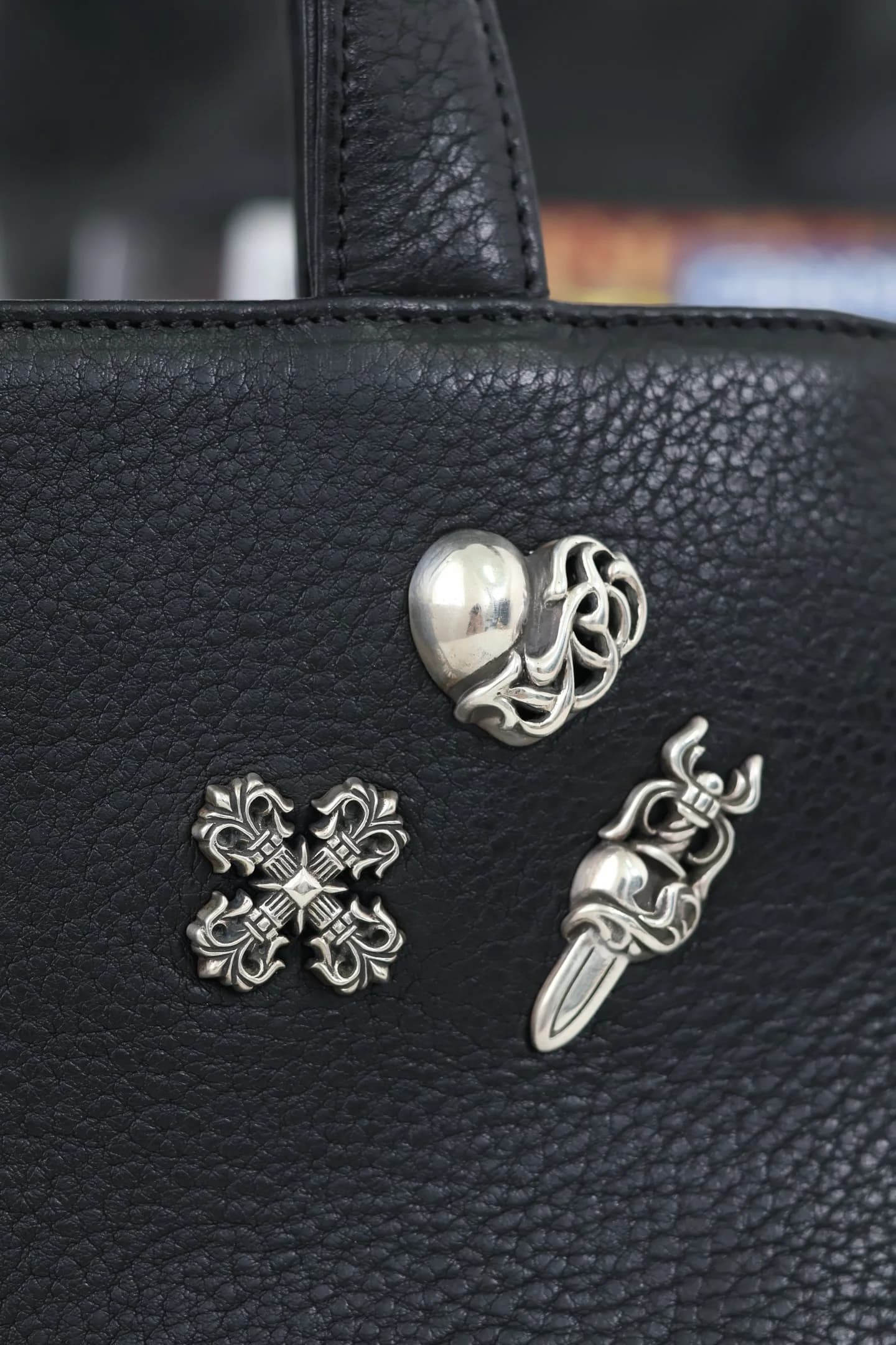 Крупный план серебряных накладок Heart, Cross и Dagger из серебра 925 пробы на сумке Chrome Hearts