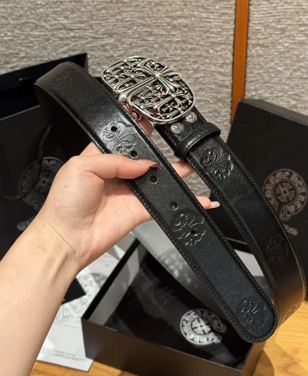 Ремень Chrome Hearts из черной кожи в руке на фоне фирменной упаковки