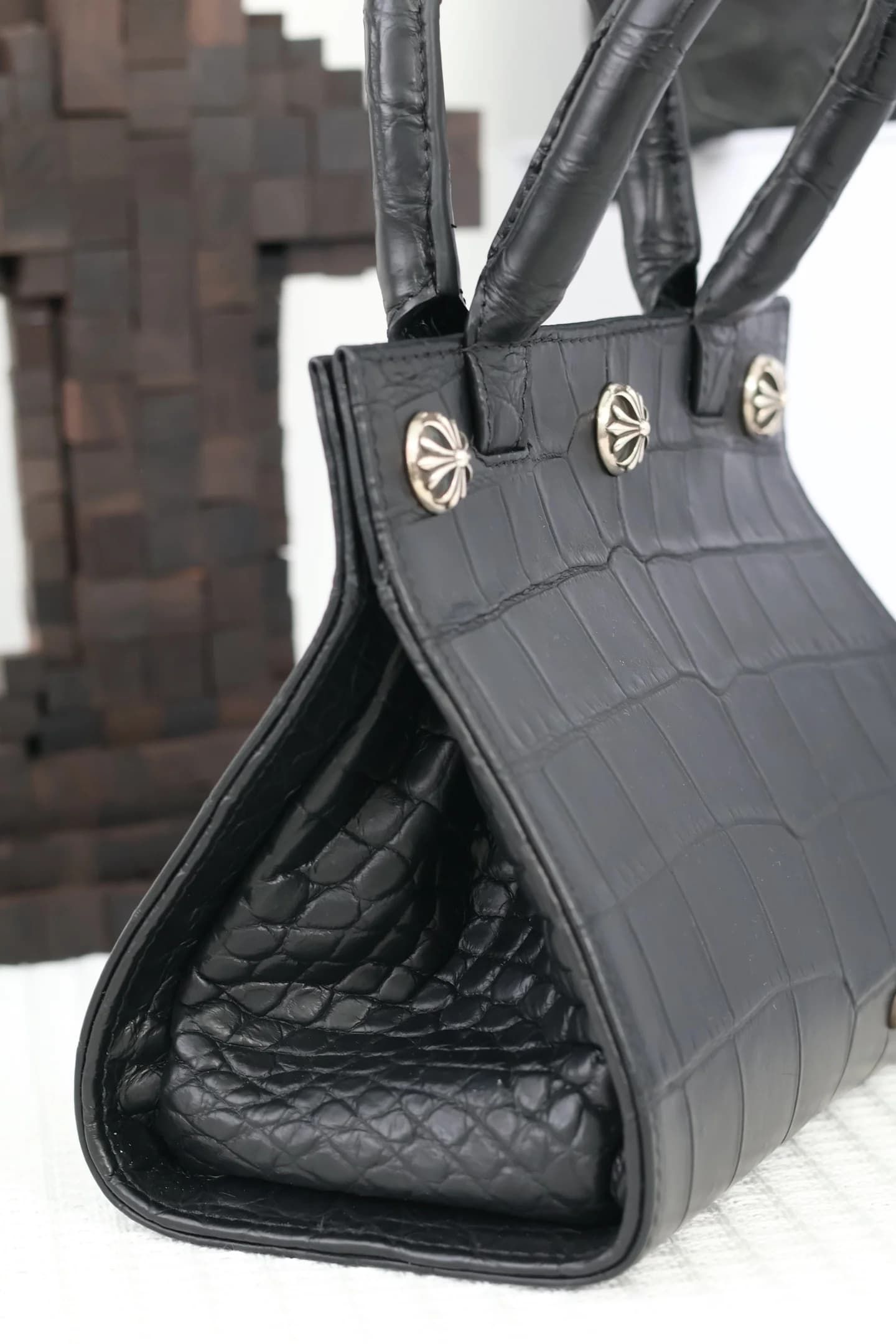 Крупный план боковой грани сумки Chrome Hearts с серебряными заклепками-крестами