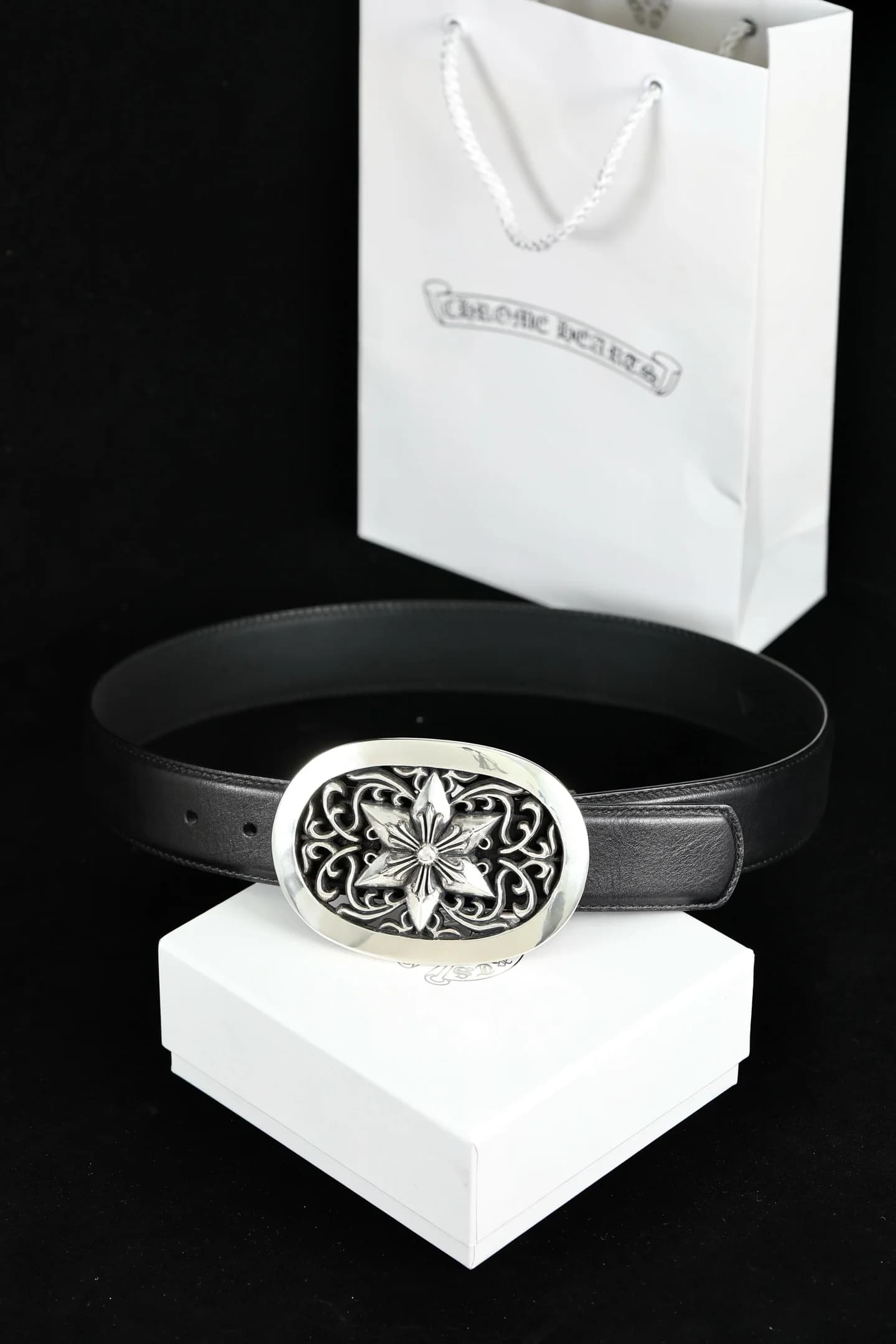 Кожаный ремень Chrome Hearts с серебряной пряжкой на подарочной коробке рядом с пакетом