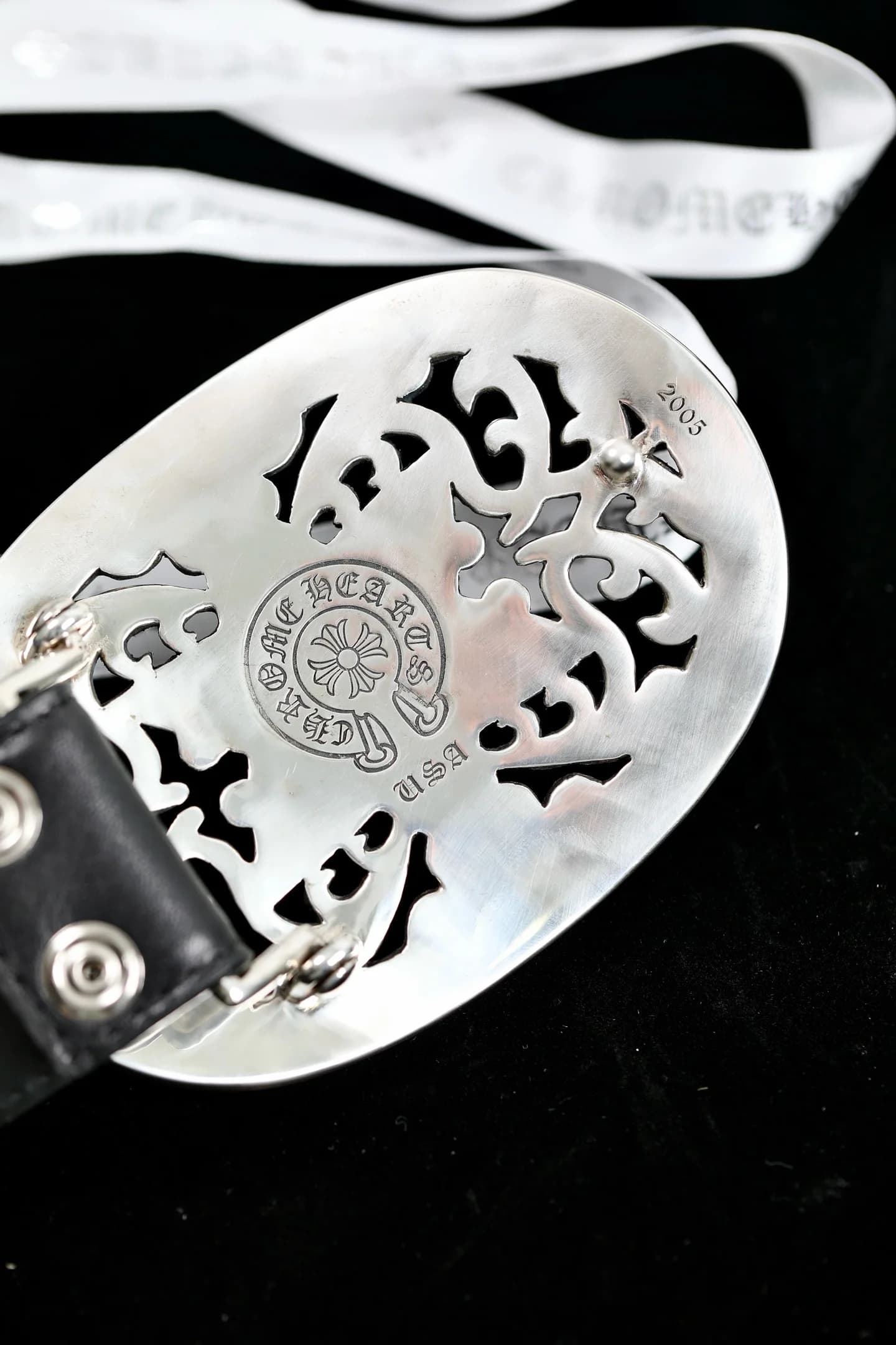 Оборотная сторона овальной пряжки Chrome Hearts с фирменной гравировкой и штампами
