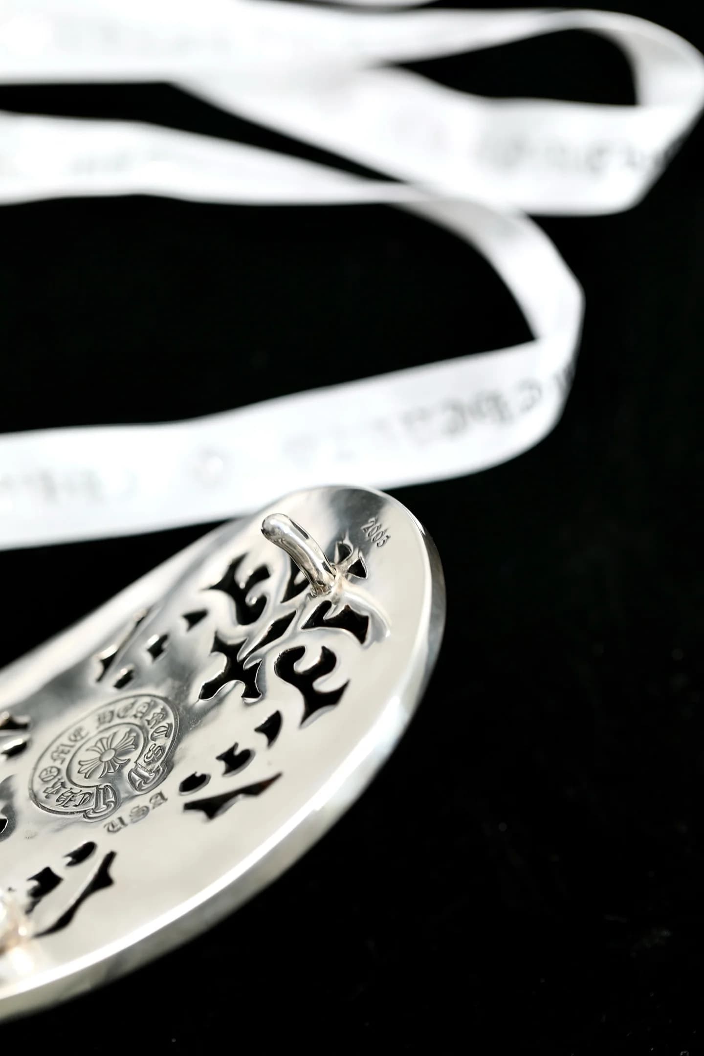Гравировка бренда на обратной стороне серебряной пряжки Chrome Hearts под углом