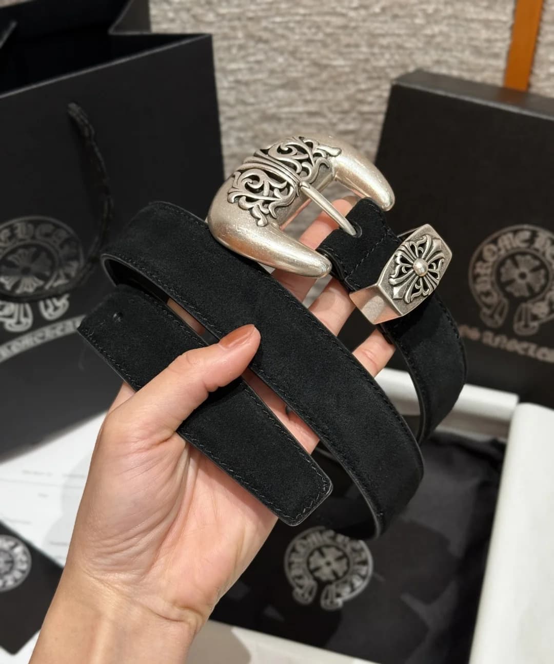Ремень из черной замши Chrome Hearts в сложенном виде в руке