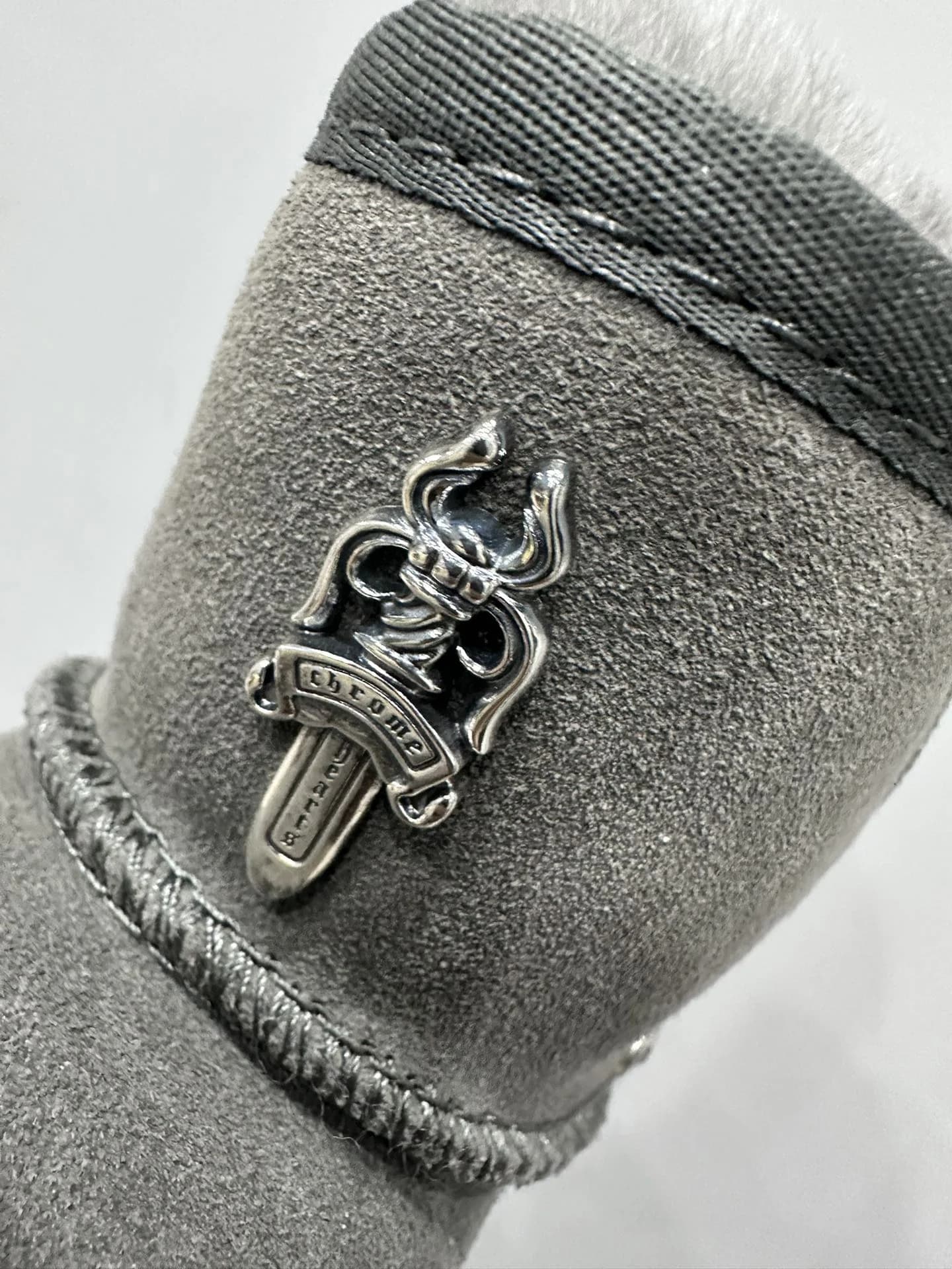 Деталь серебряной фурнитуры в виде кинжала Chrome Hearts на замшевых сапогах
