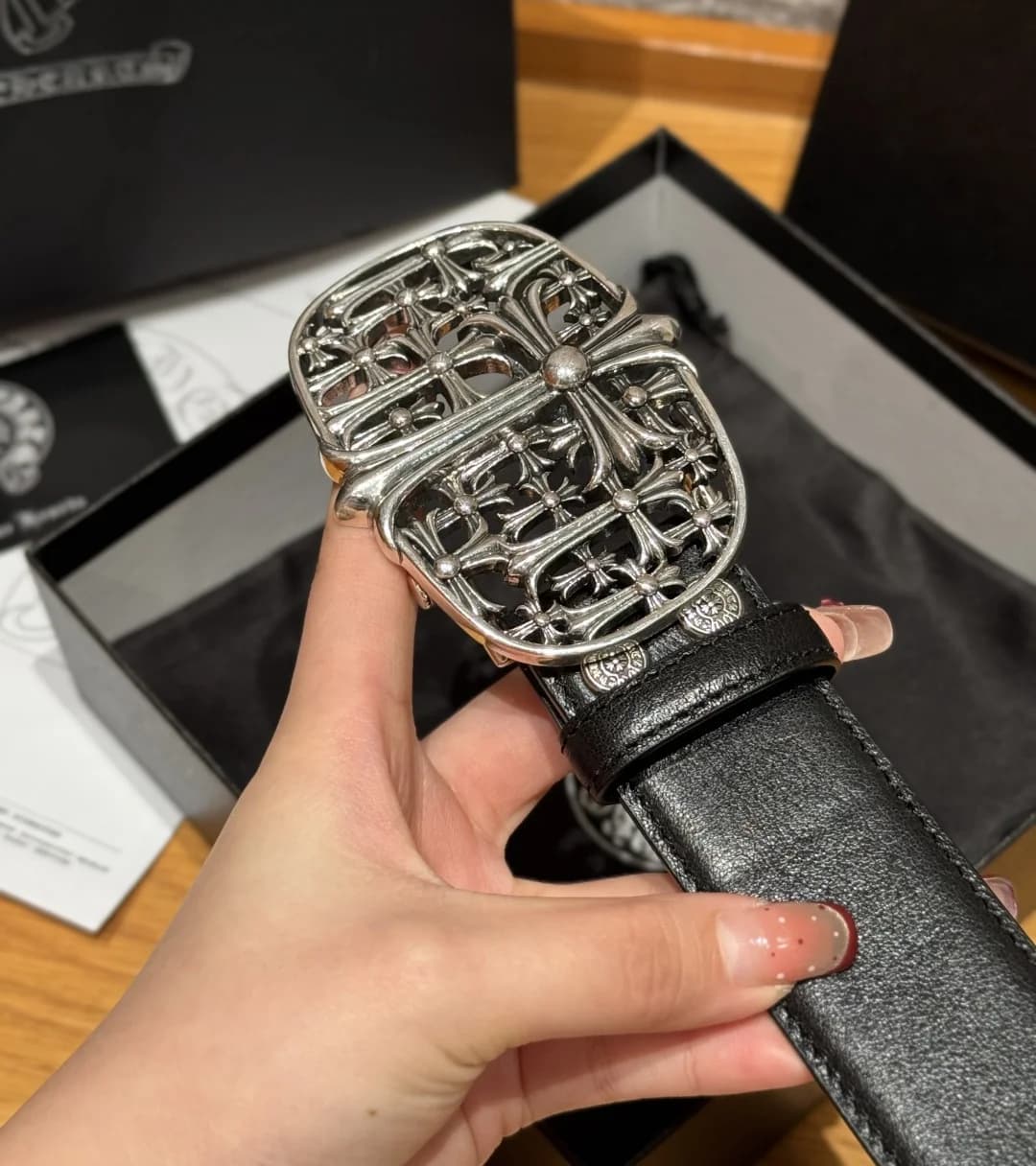 Крупный план резной металлической пряжки ремня Chrome Hearts с крестами и кинжалом