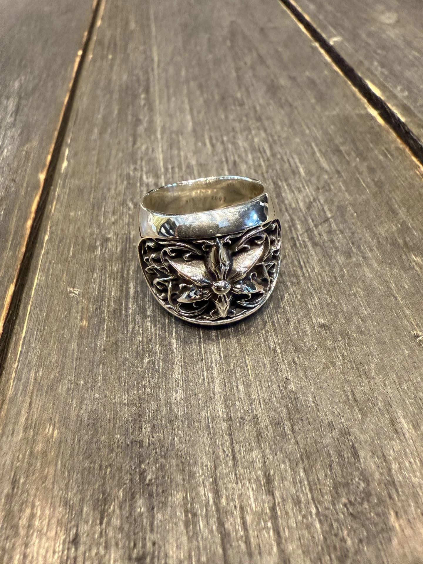 Серебряное кольцо Chrome Hearts Star Ring с объемным узором на деревянной поверхности