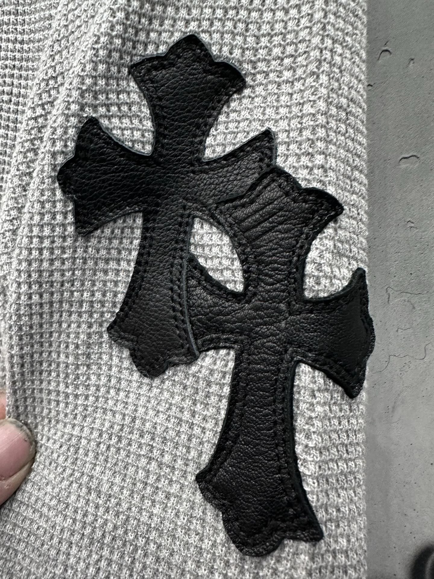 Деталь рукава лонгслива Chrome Hearts с нашивками в виде кожаных крестов