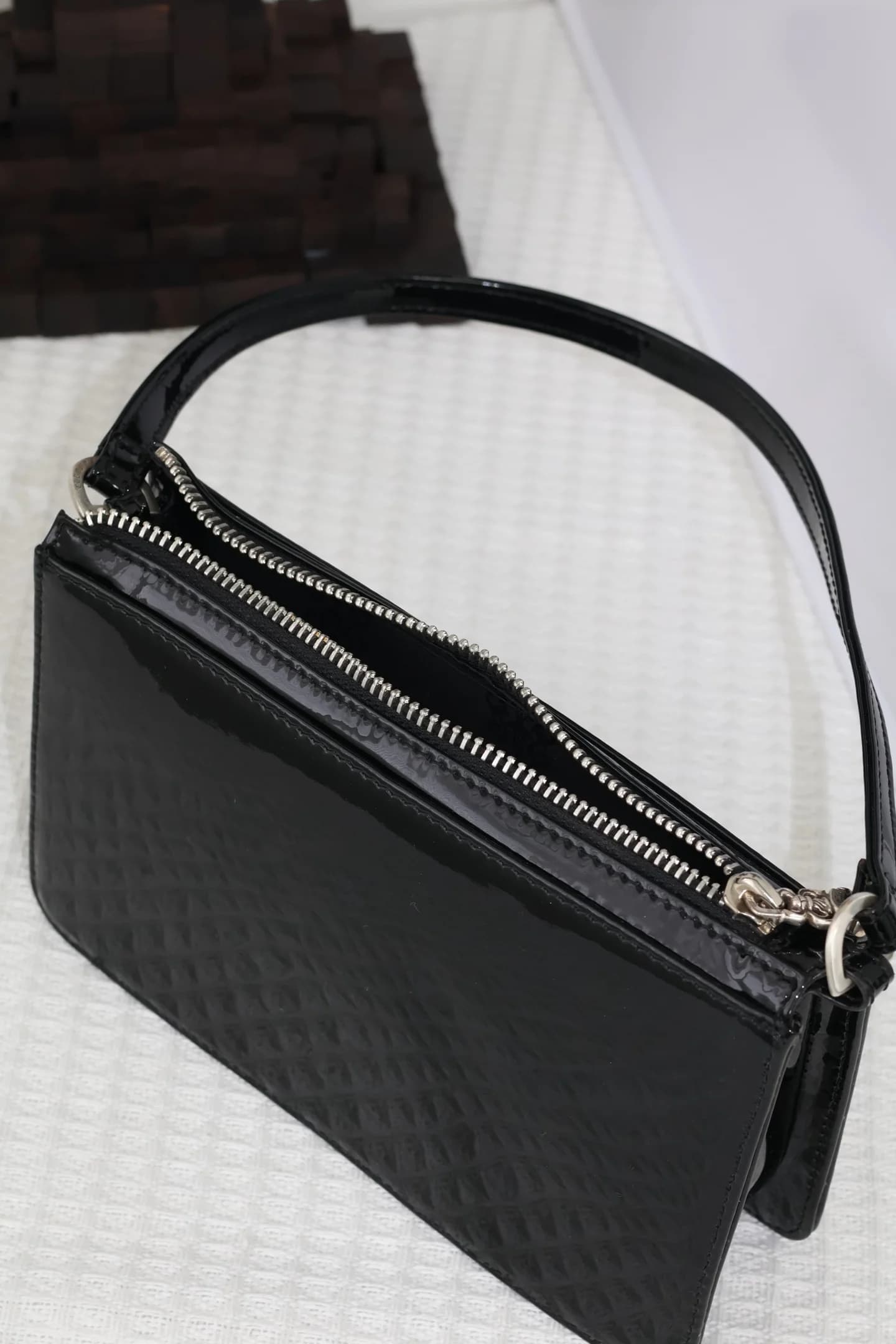 Вид сверху на молнию и верхнюю ручку лакированной сумки Chrome Hearts