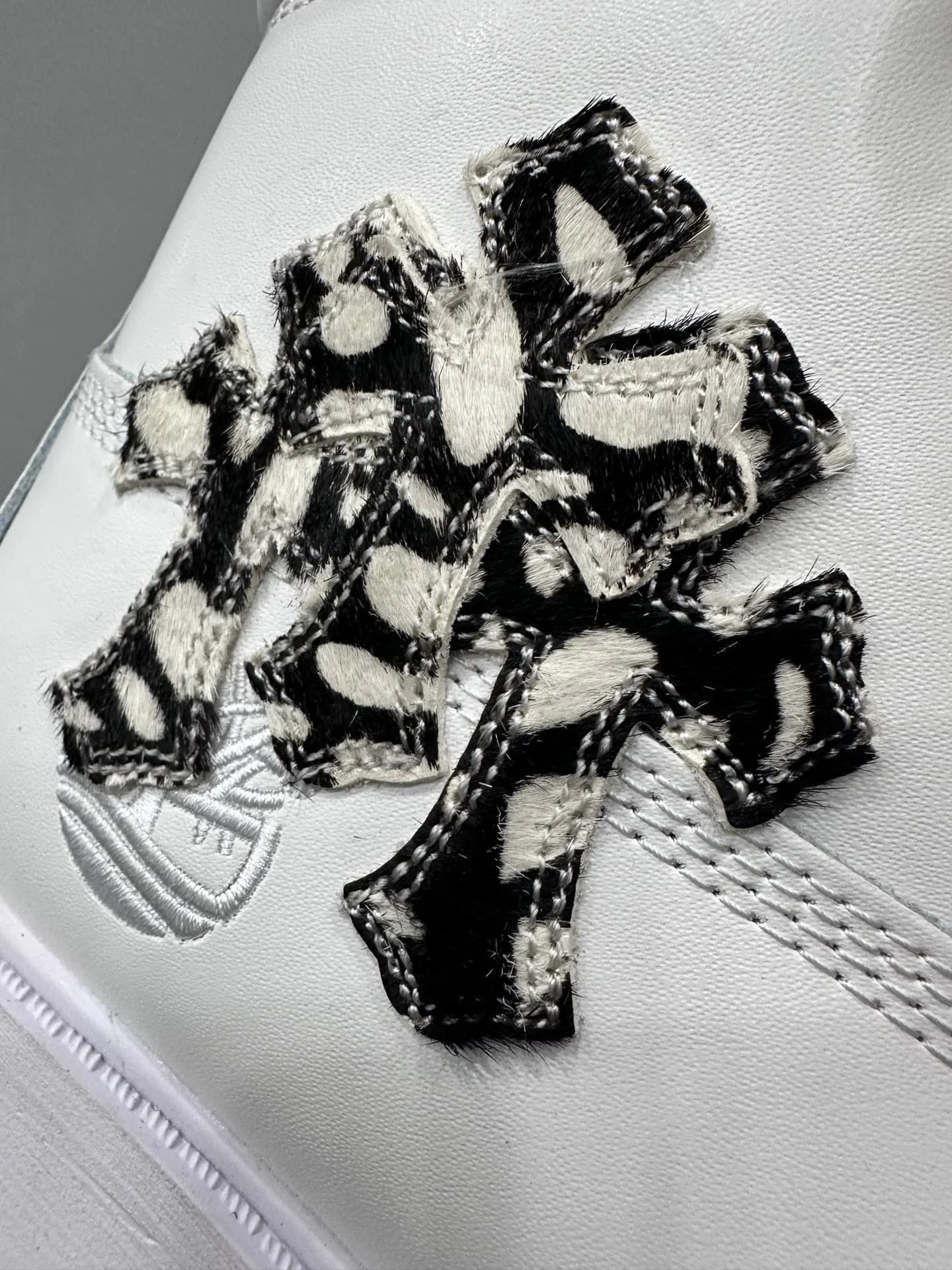 Крупный план нашивки в виде креста с пятнистым принтом на ботинках Chrome Hearts