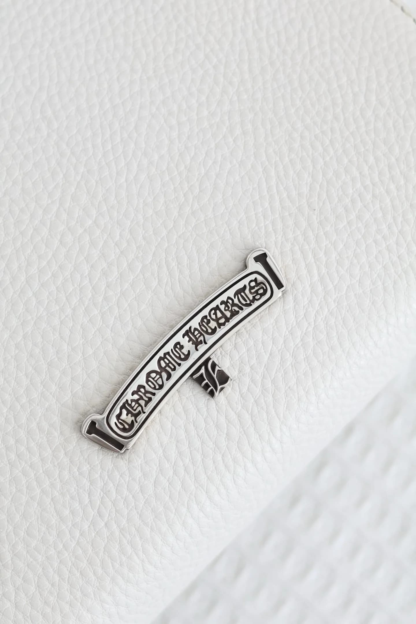 Деталь задней стороны сумки с серебряным логотипом-скроллом Chrome Hearts