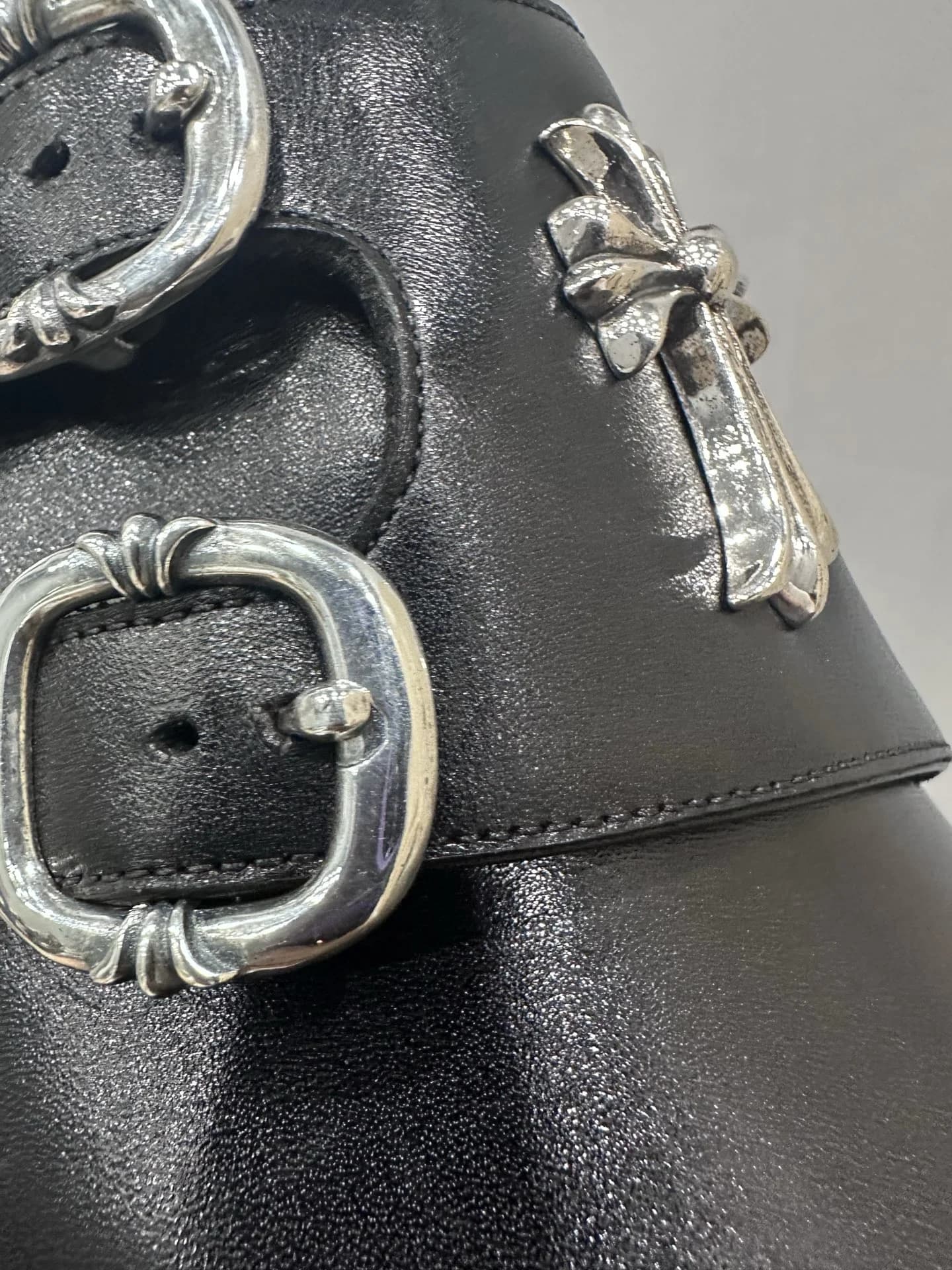 Крупный план серебряной пряжки и креста на туфлях Chrome Hearts x John Lobb