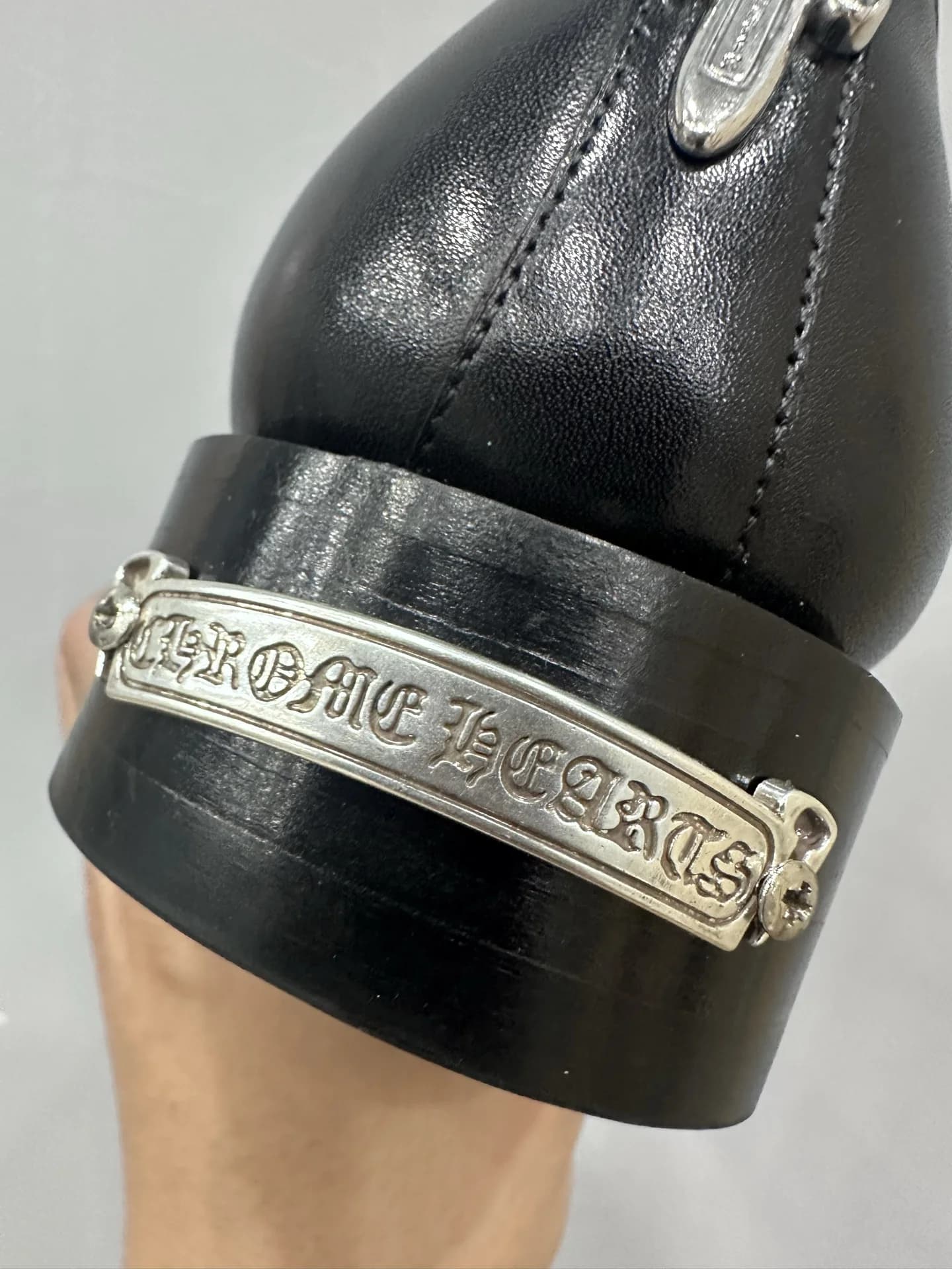 Крупный план серебряной пластины с логотипом Chrome Hearts на каблуке