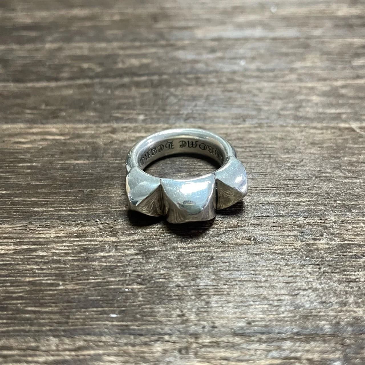 Серебряное кольцо Chrome Hearts с тремя пирамидальными выступами на деревянном фоне