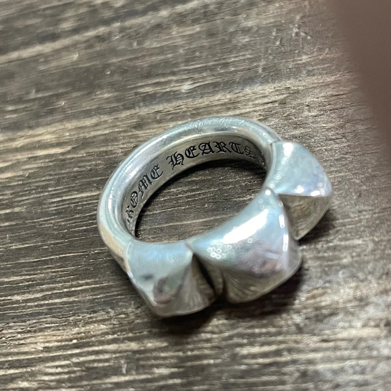 Крупный план объемных пирамидальных шипов и внутренней гравировки Chrome Hearts на кольце