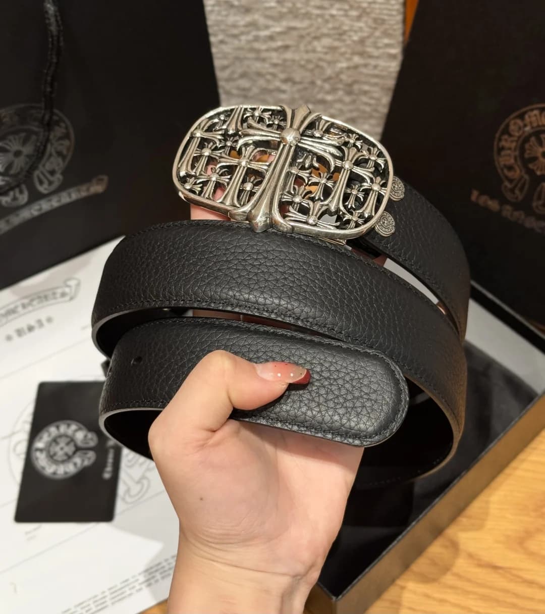 Свернутый черный ремень Chrome Hearts из зернистой кожи в руке