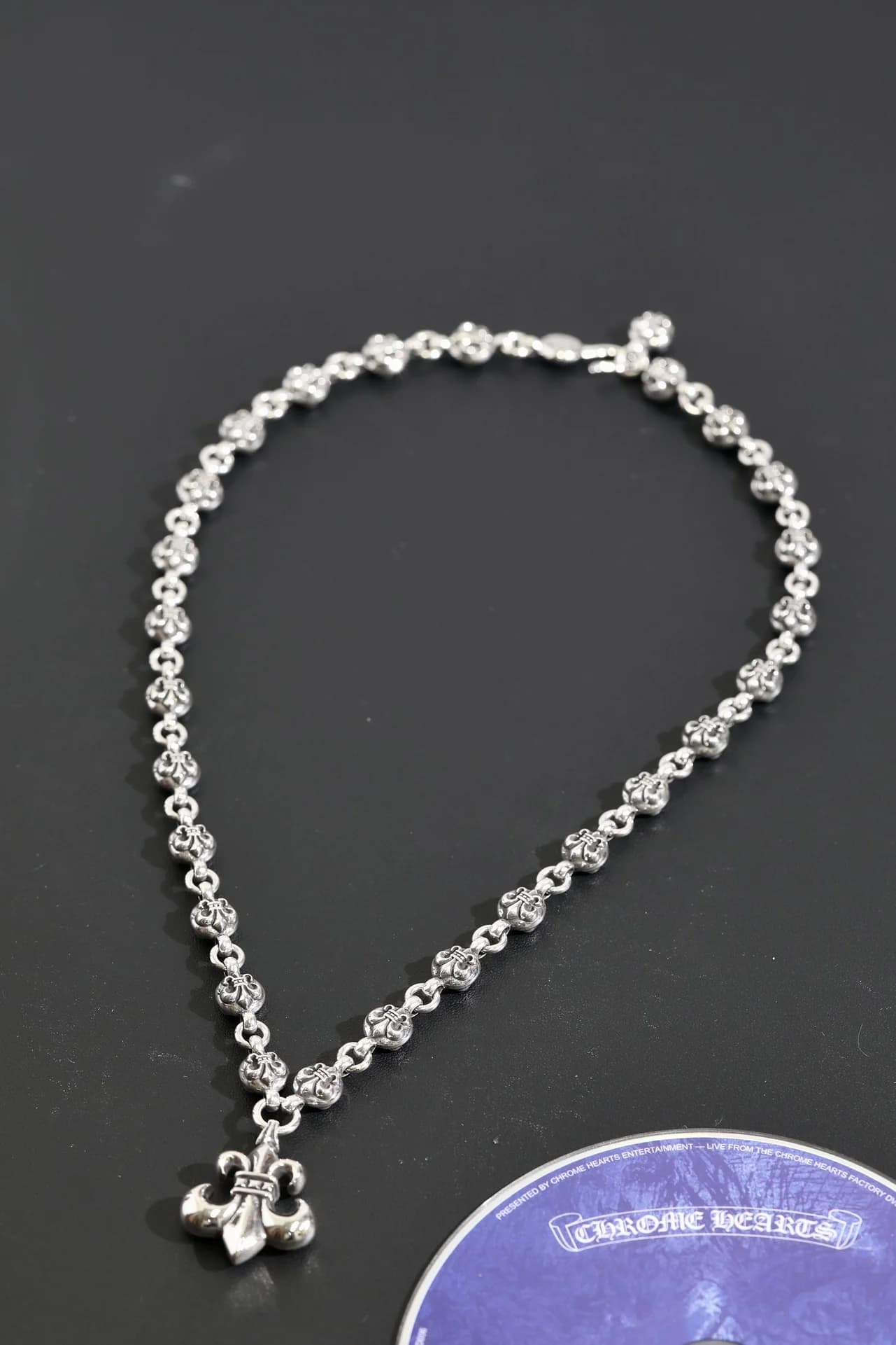 Серебряное колье с резными звеньями и кулоном BS Fleur на темном фоне