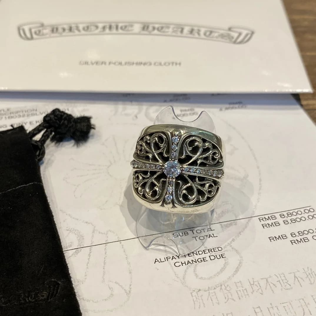 Фронтальный вид кольца Chrome Hearts Oval Cross на фоне документов