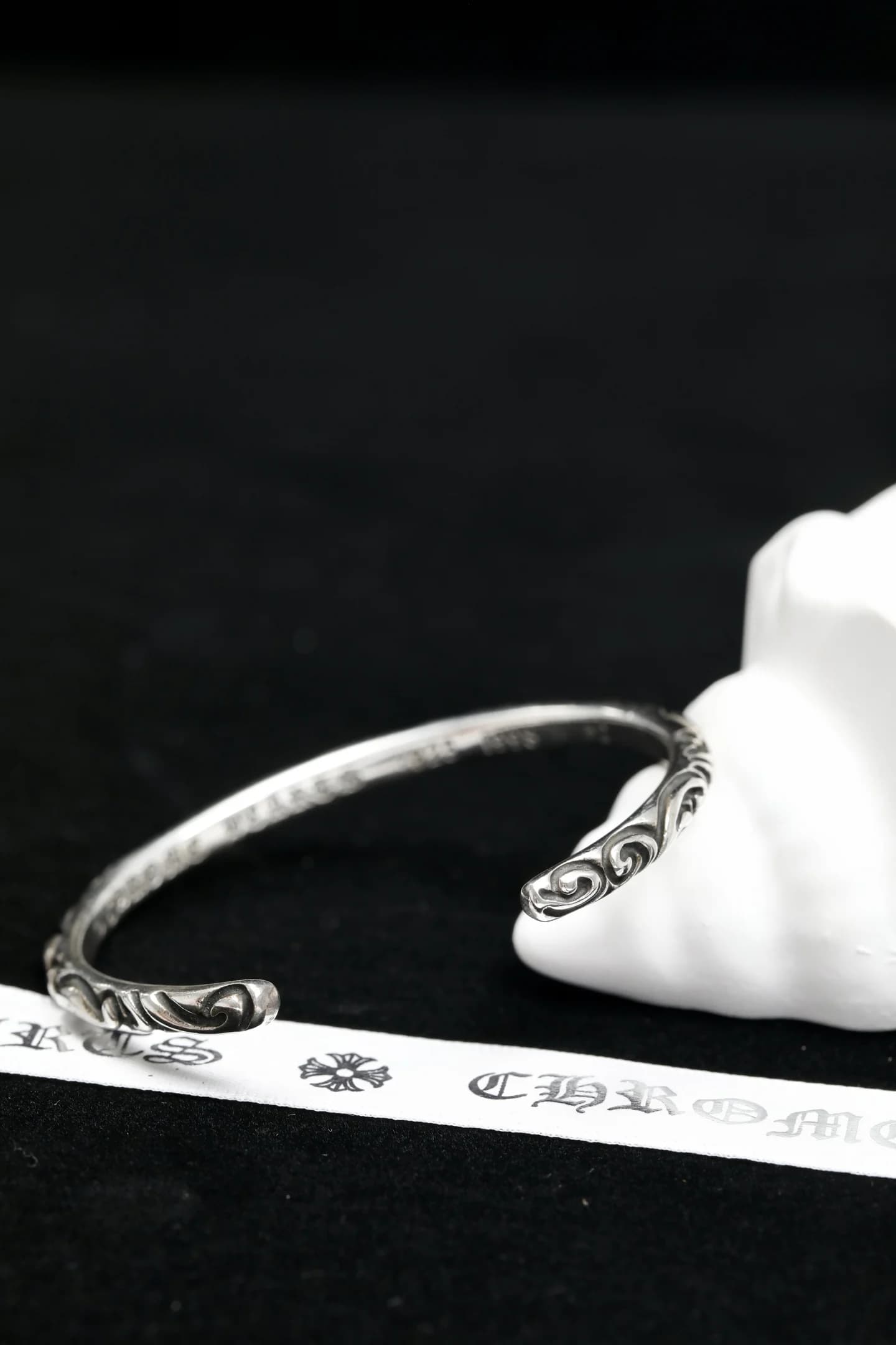 Вид сбоку на серебряный браслет-кафф Chrome Hearts с рельефным узором