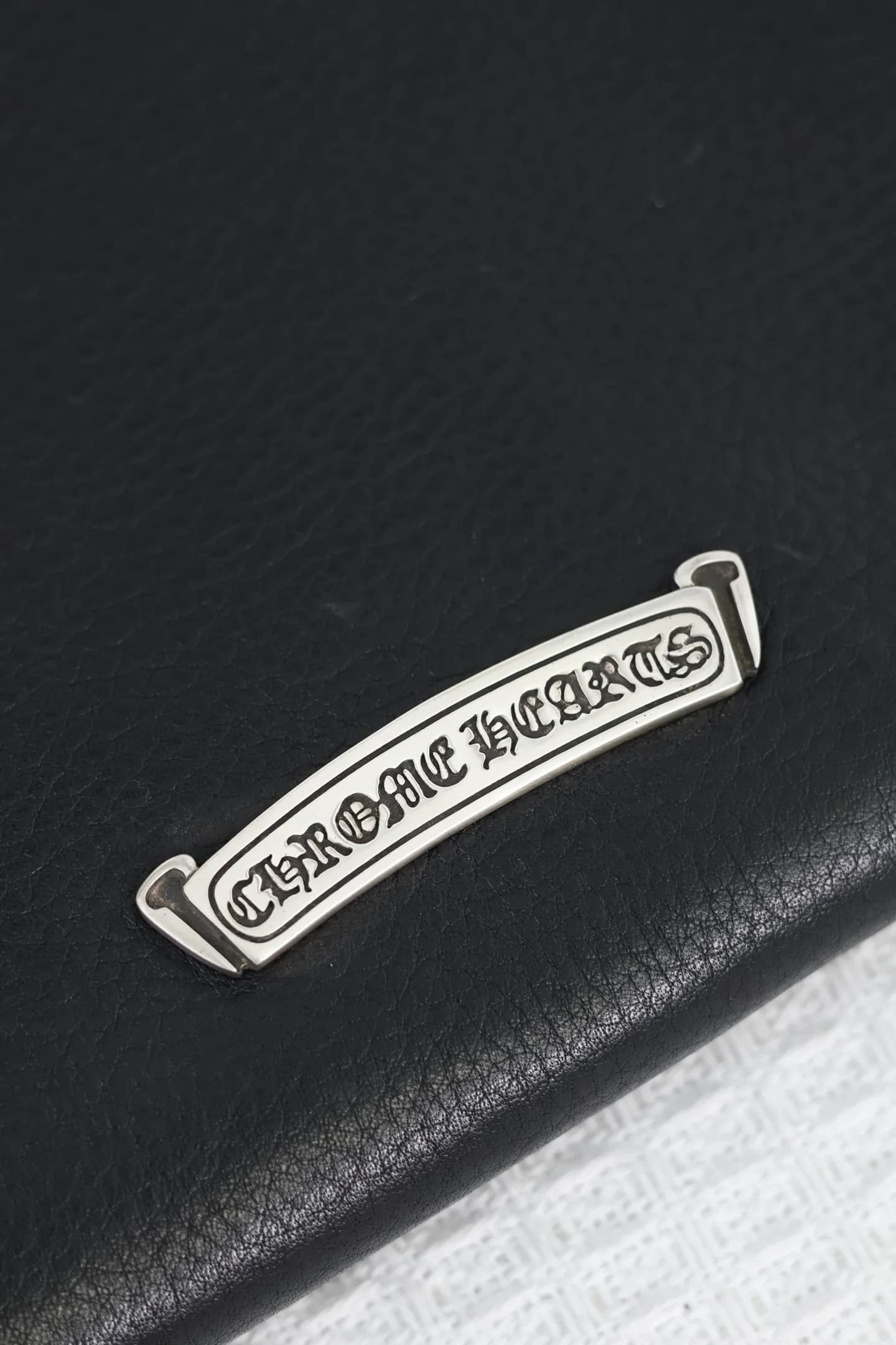 Серебряная плашка с гравировкой Chrome Hearts на задней панели сумки
