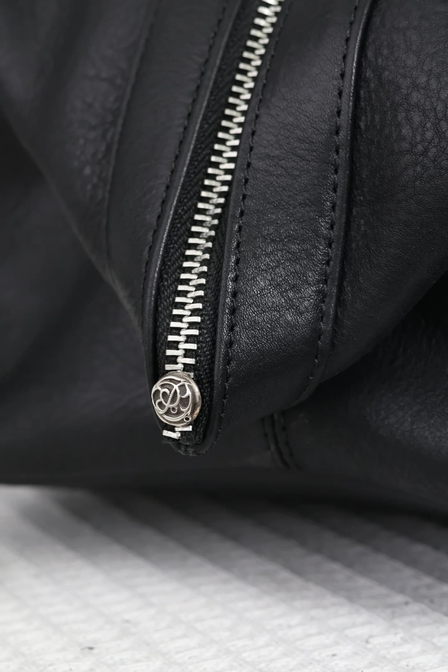 Фирменная серебряная заклёпка на застёжке-молнии сумки Chrome Hearts
