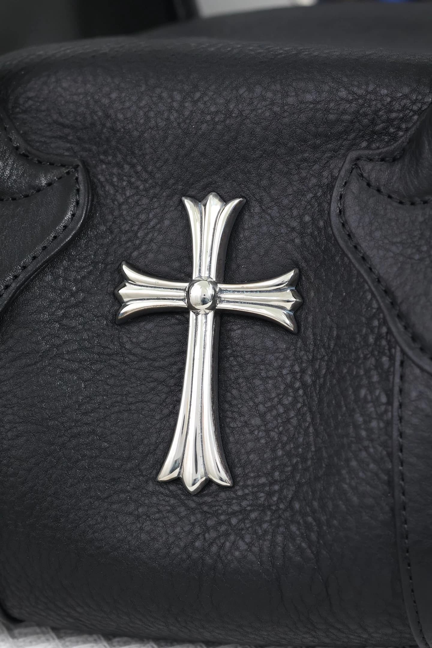 Деталь серебряного креста Chrome Hearts на фактурной коже