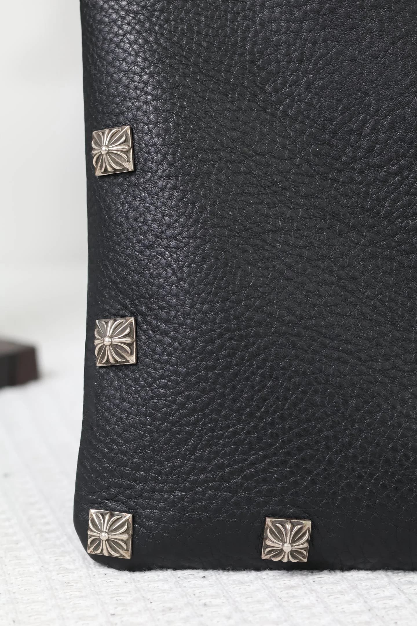 Крупный план фактуры кожи и серебряных заклепок Chrome Hearts